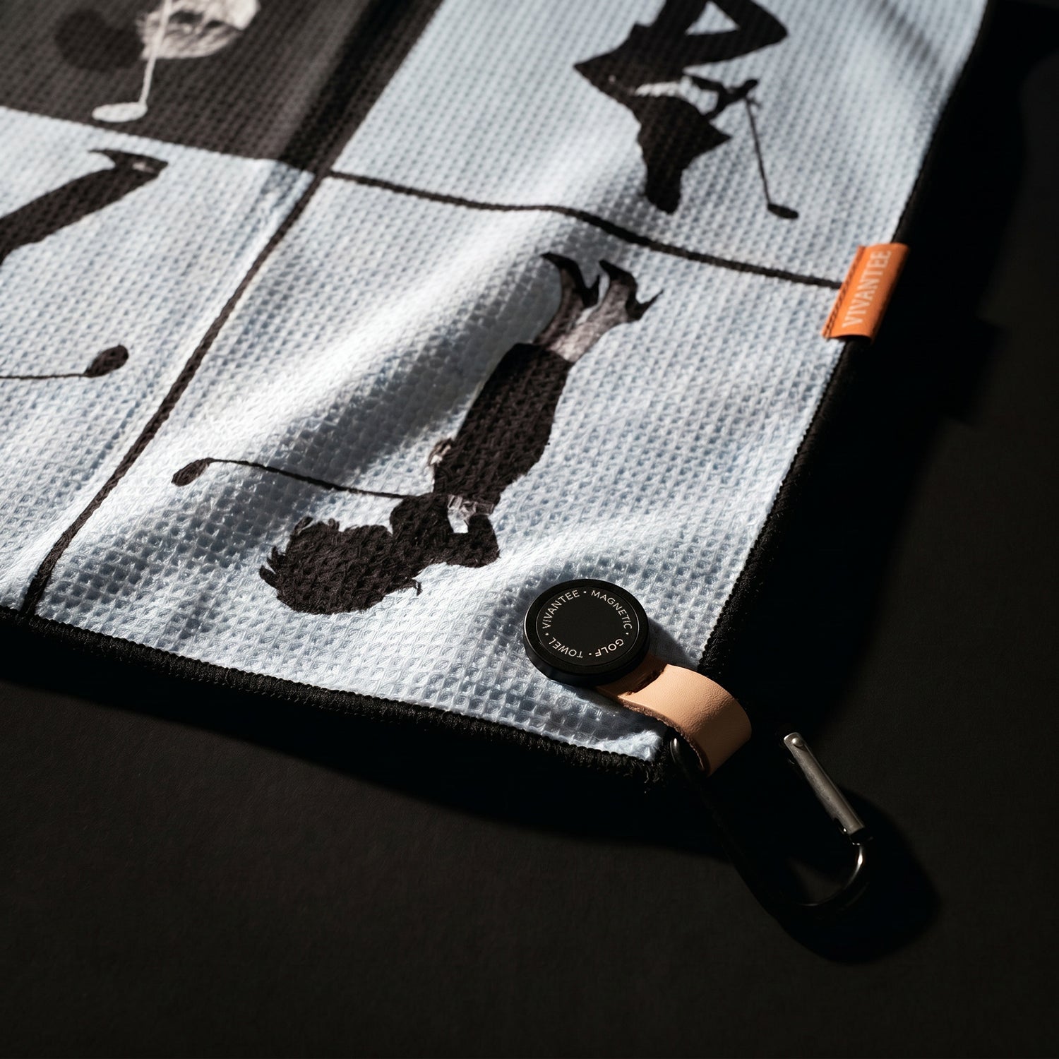 Black and white patterned magnetic golf towel with silhouettes of people playing golf.