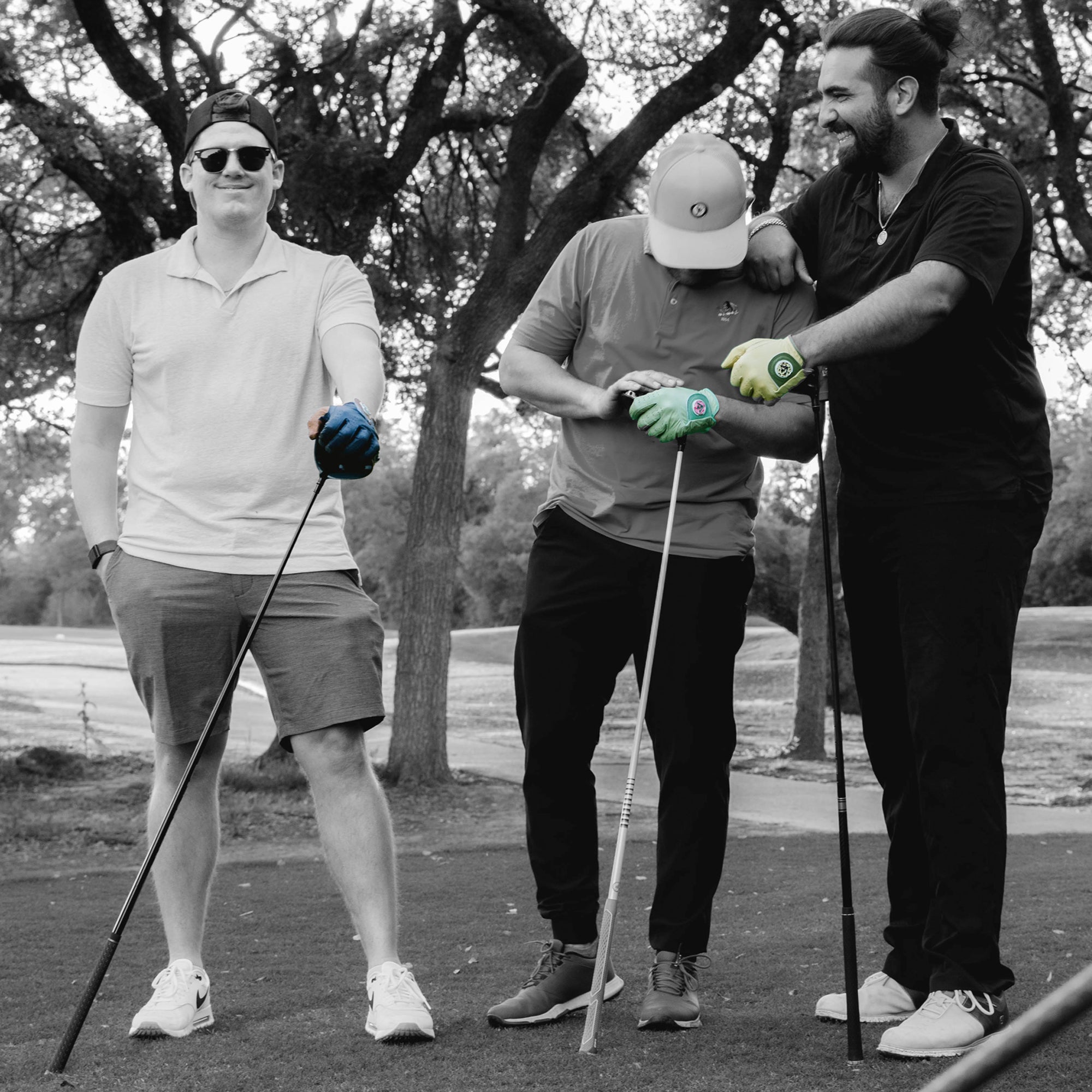 Men golfing on the tee box waiting with someone lines up in monochromatic showing unique golf gloves with magnetic ball markers in various colors.