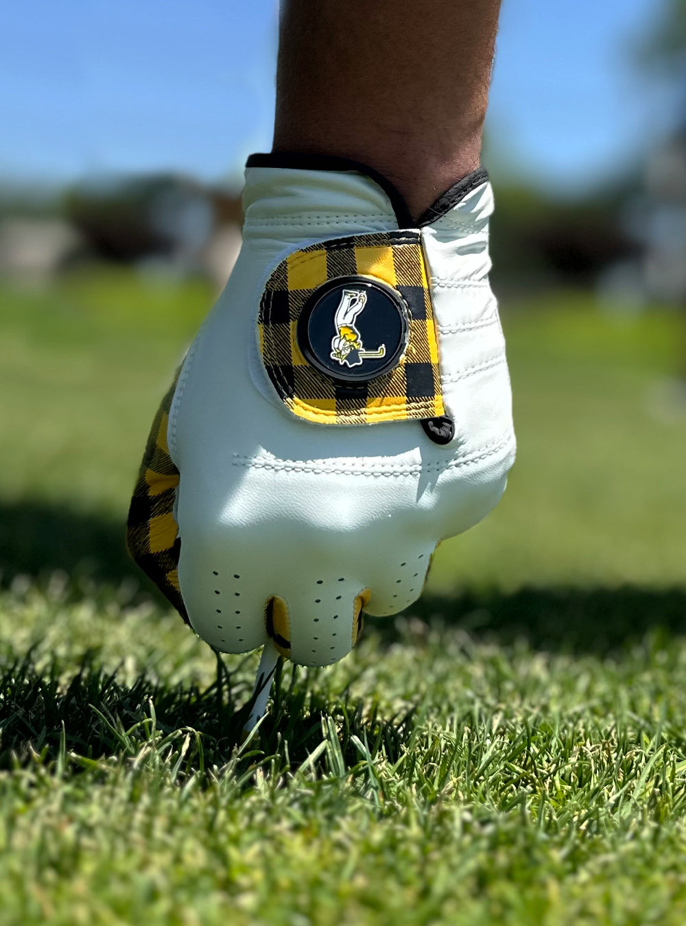 Close up of a custom golf glove by VivanTee golf for the Mountaineers putting in a golf tee into the ground.