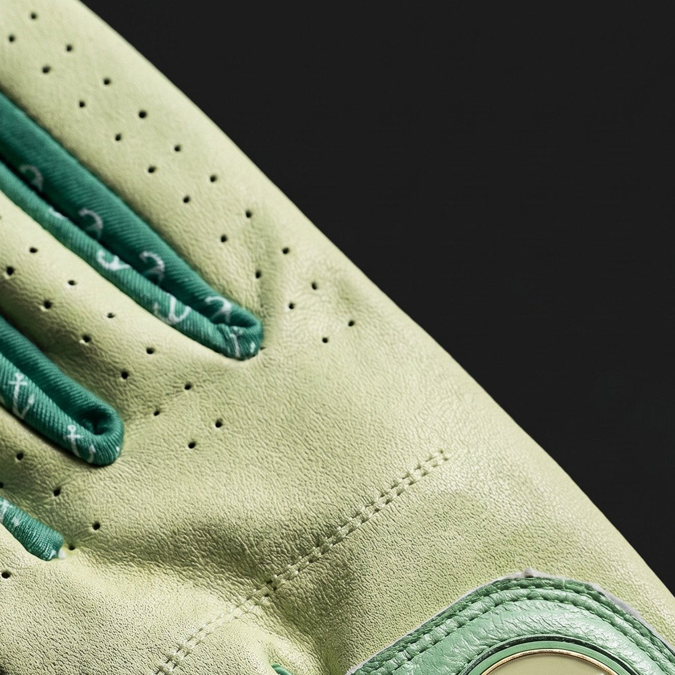 Close-up of a green golf glove with a brand logo on a black background