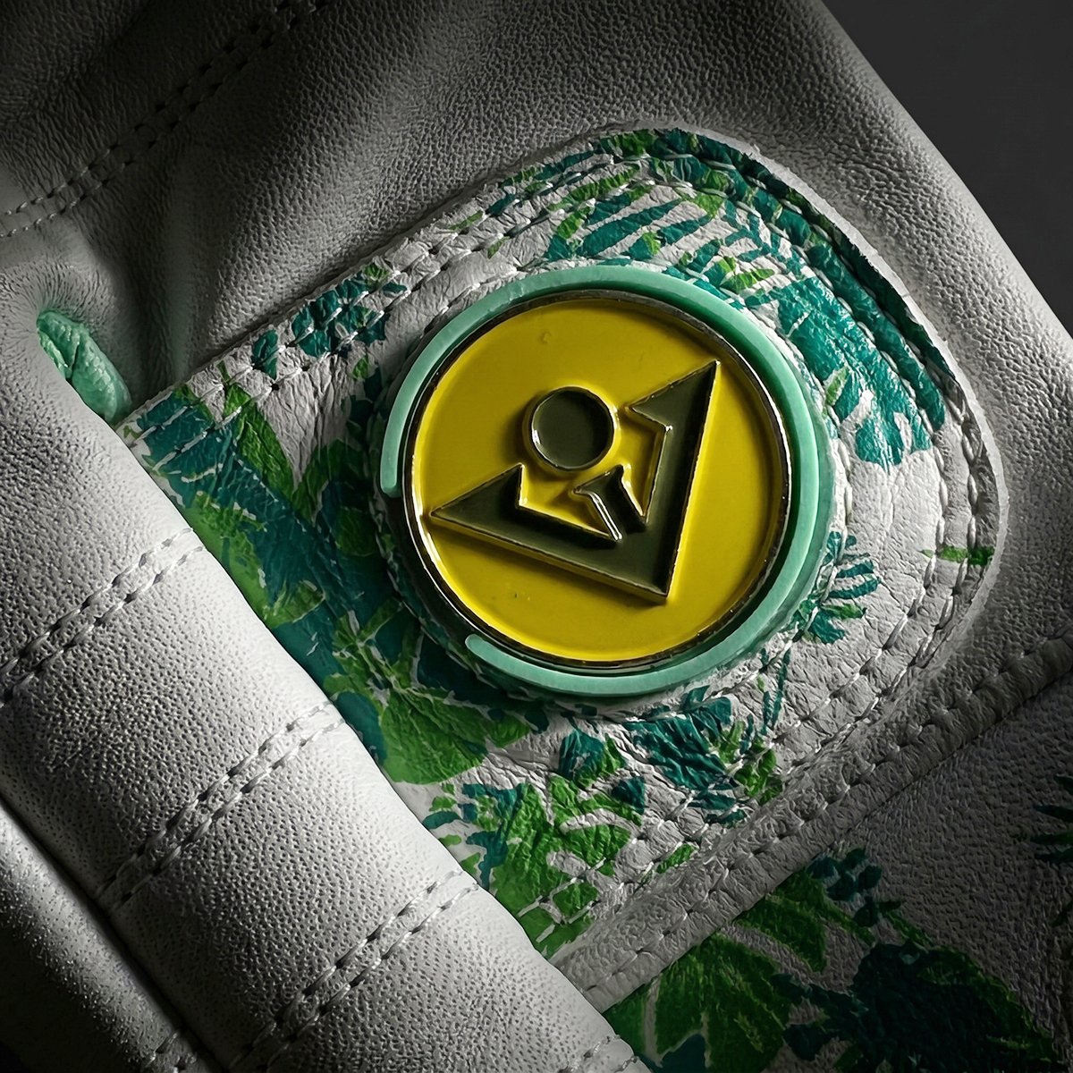 Close-up of a green and yellow vivantee golf magnetic ball marker on a textured surface