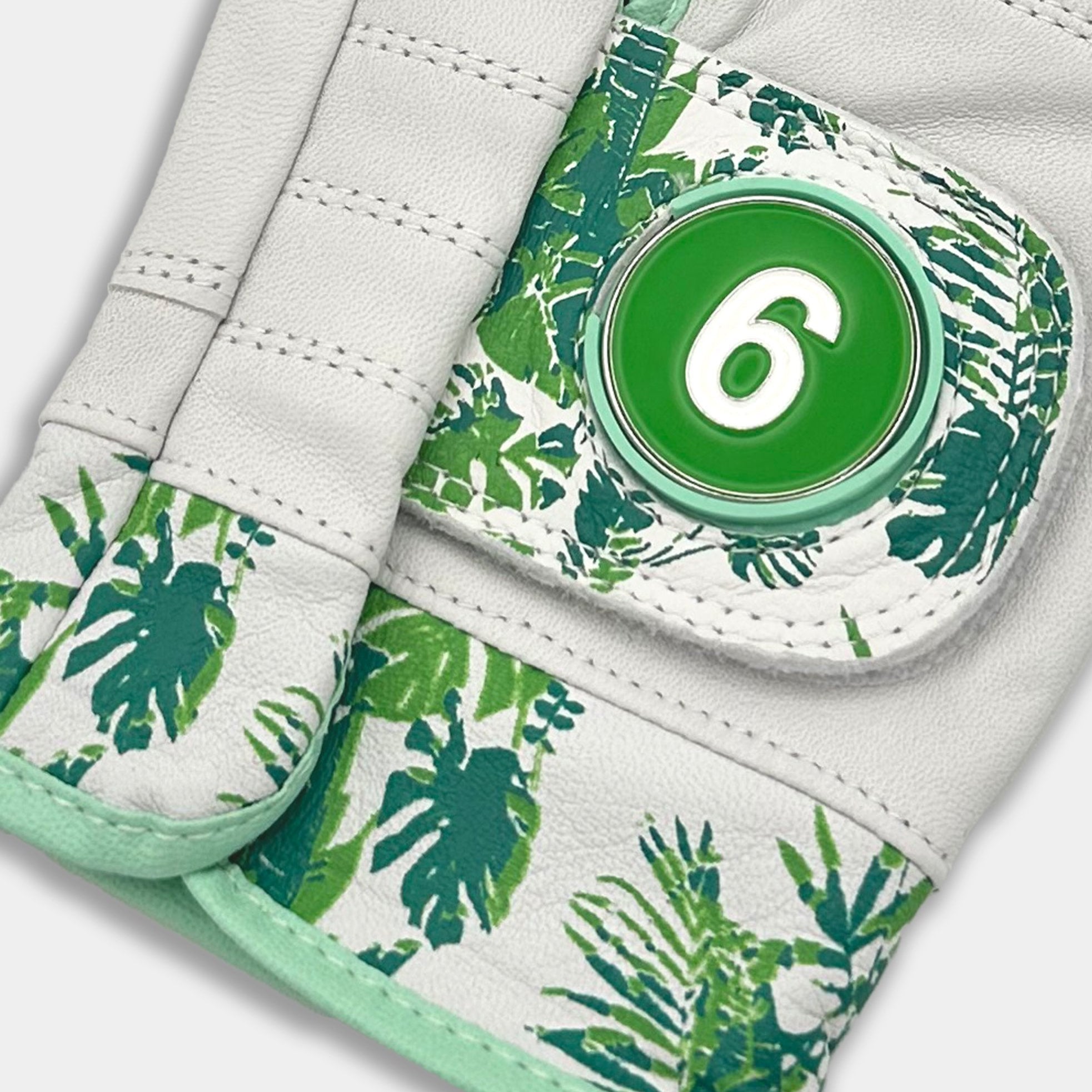Glove with green leaf pattern and a button on a white background.