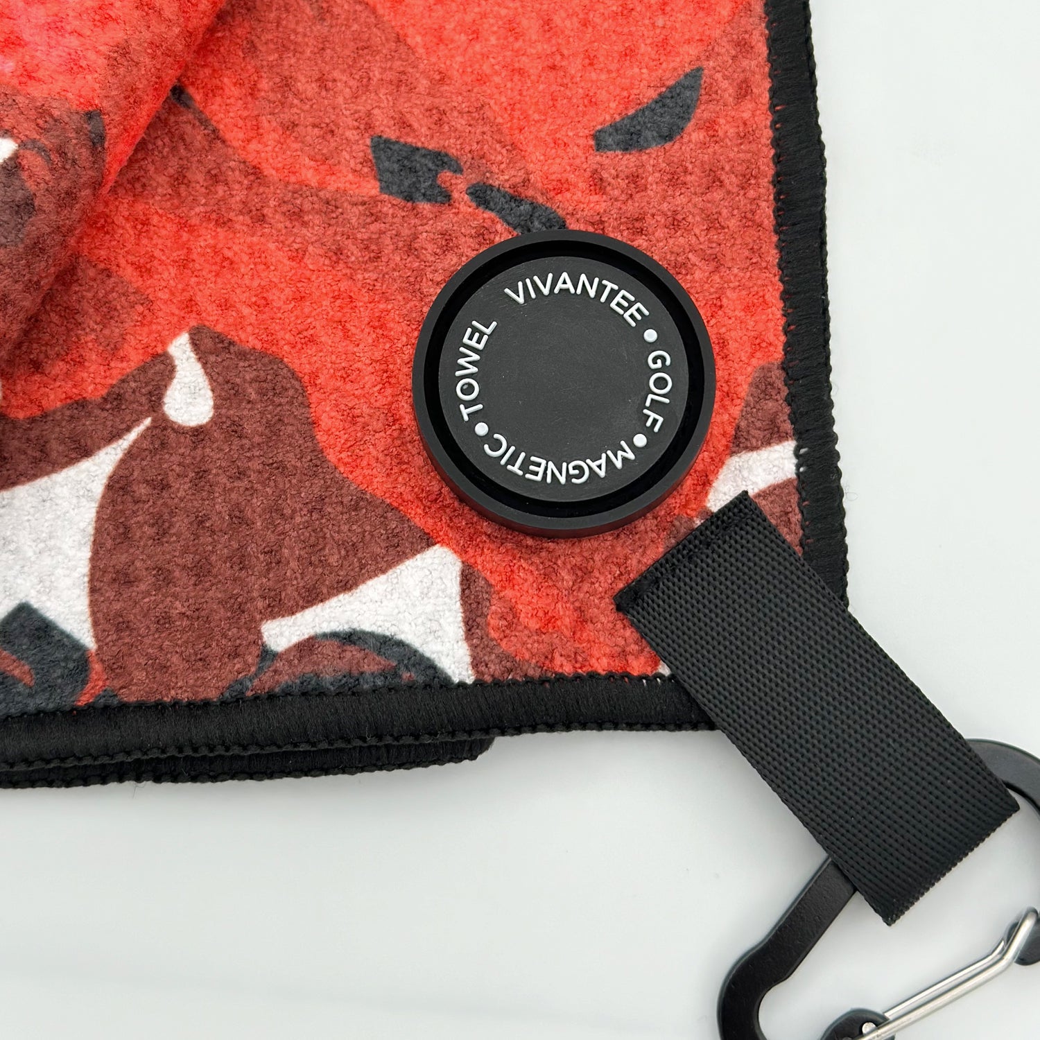 Close up of VivanTee magnet attachment to Central Petal golf towel in red and black.