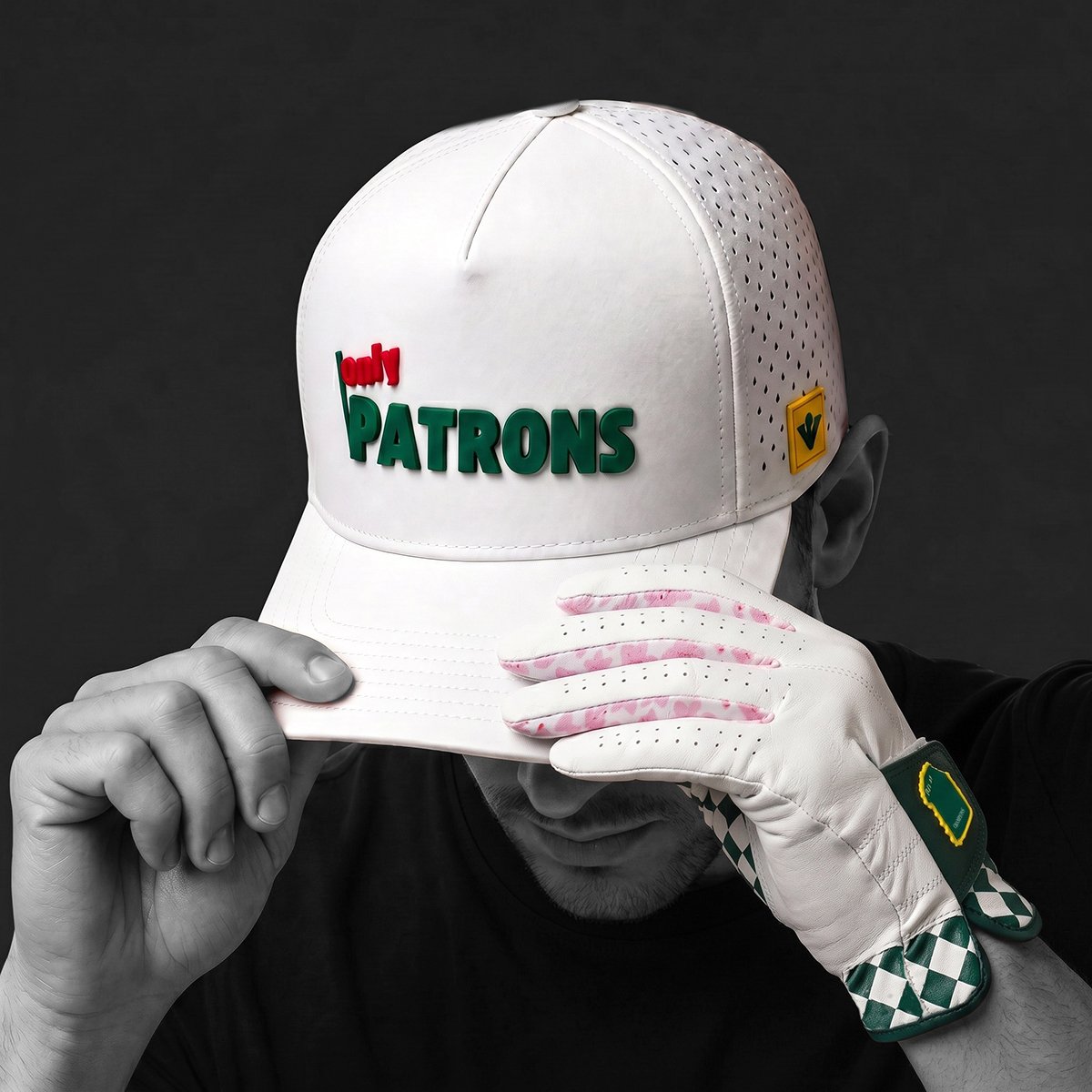 Person wearing a white golf cap with 'Only Patrons' branding and a golf glove with magnetic ball marker, on a dark background.