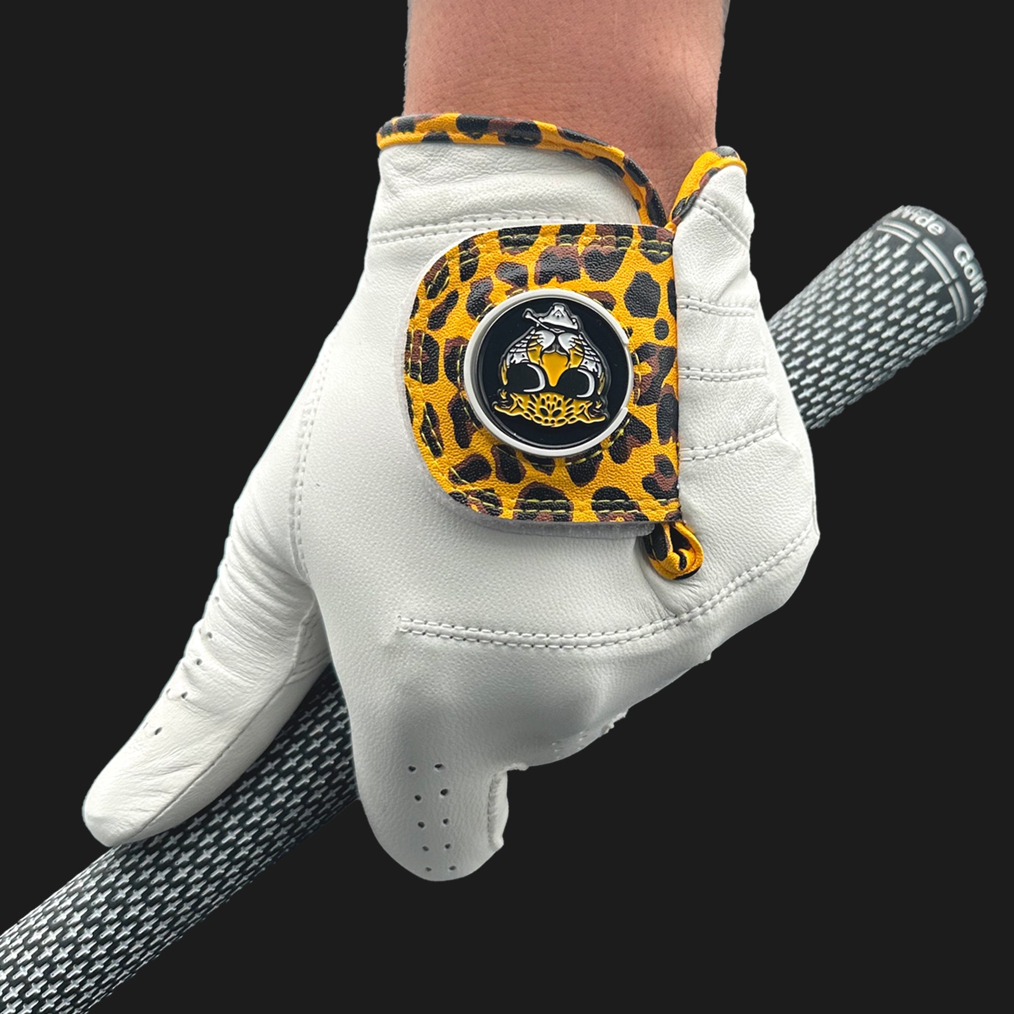 Cheetah print golf glove with magnetic ball marker close up gripping a golf club with golf pride grips.