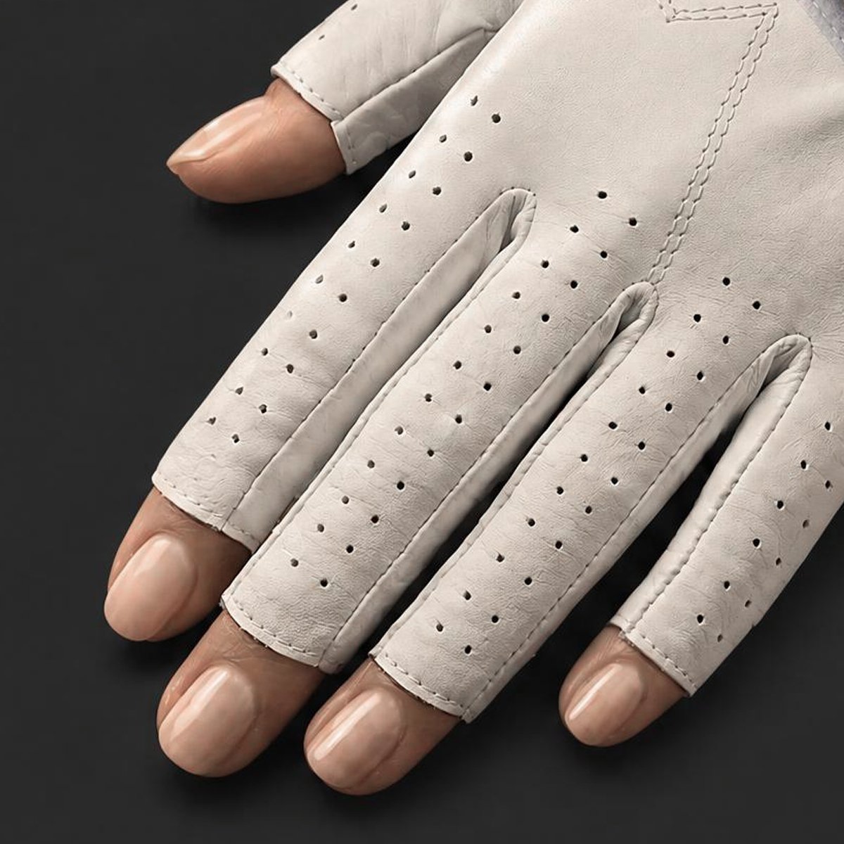 Close up of VivanTee Golf's fingerless golf gloves with a well manicured woman's hand on a black background.