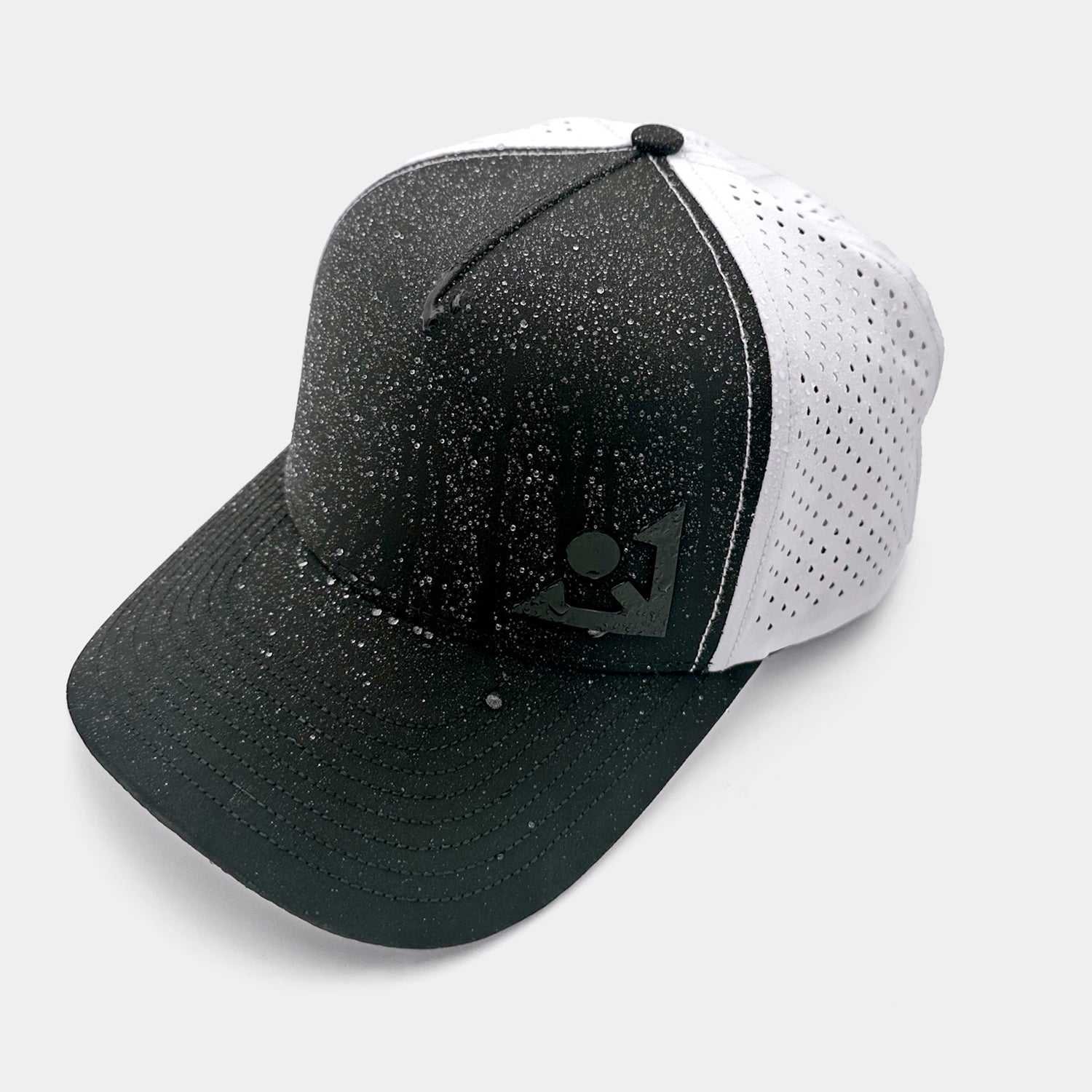 Black and white golf cap with a logo on a light gray background and water drops showing it's water repellant features.