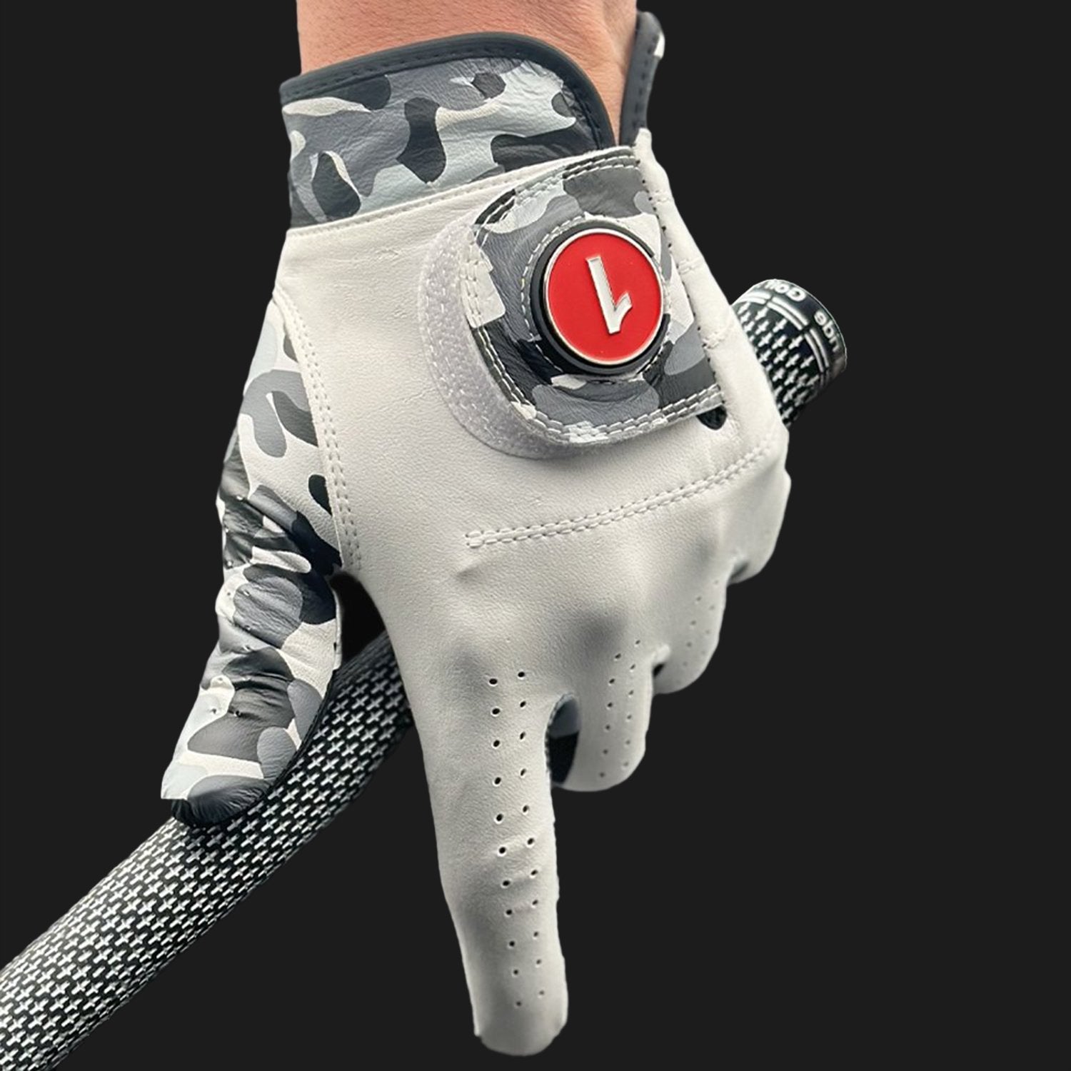 Golf glove with a camouflage pattern on the back and a red logo on the palm, held by a hand.