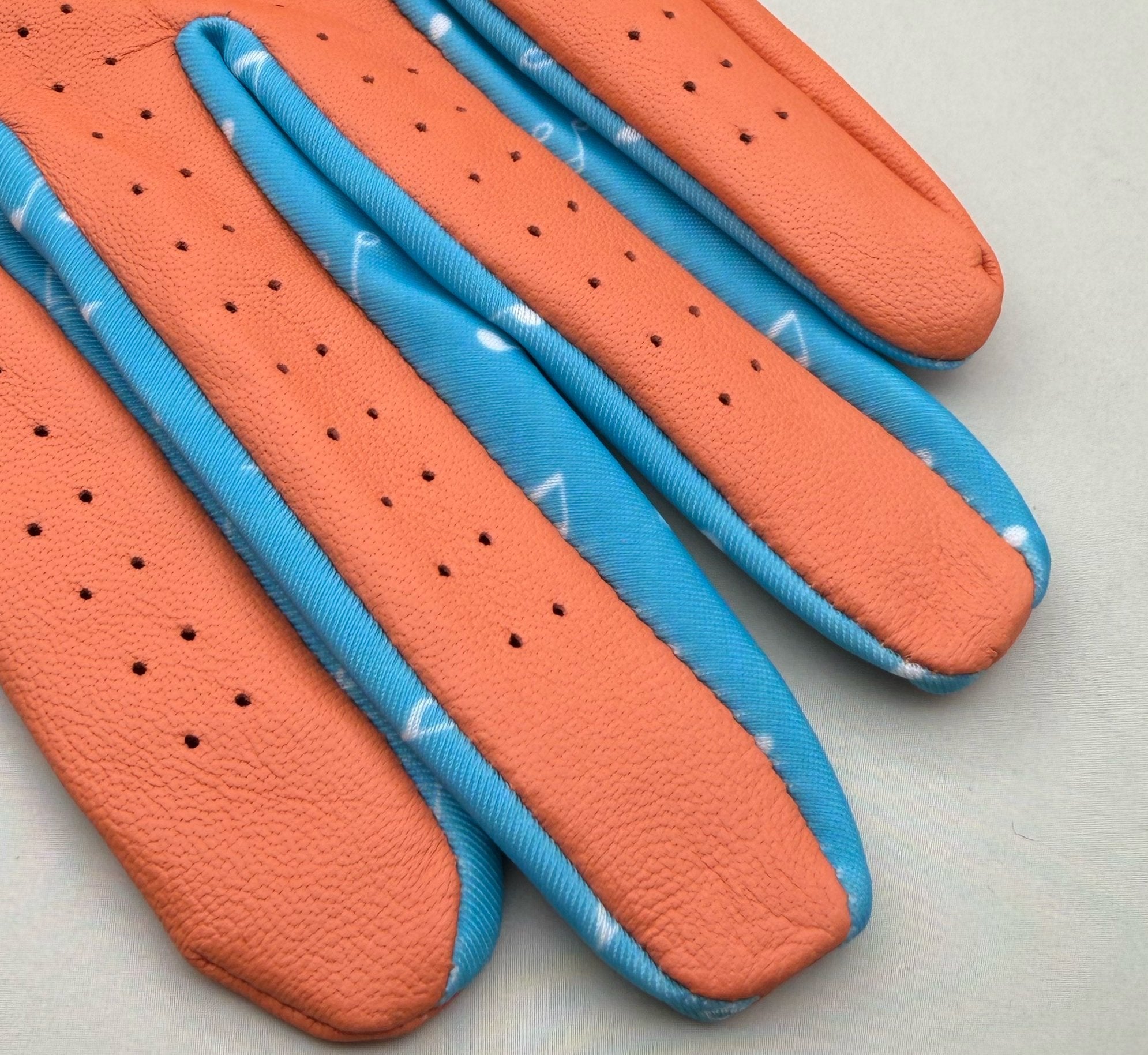 Close up of golf glove fingers featuring orange and blue golf glove with lycra