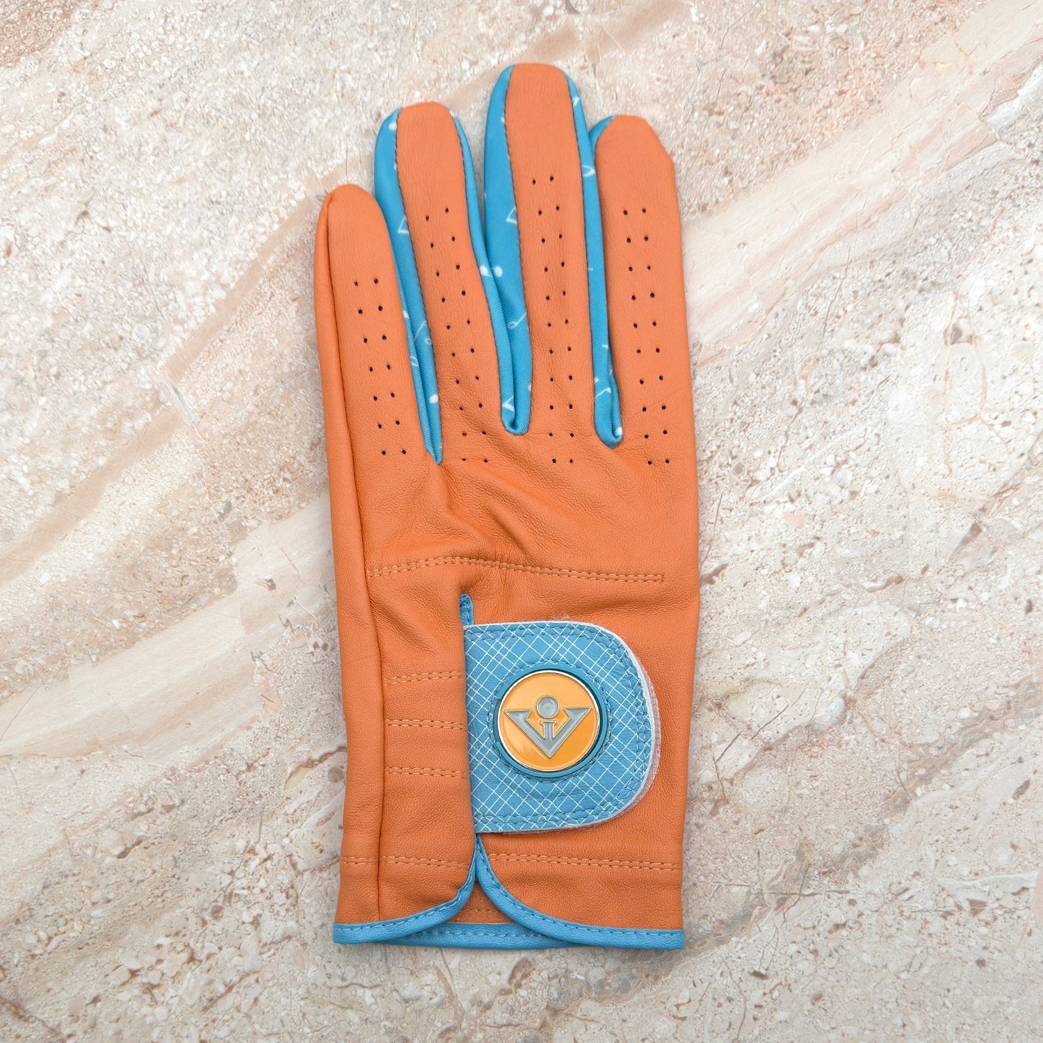 Orange and blue golf glove with magnetic ball markers on a granite counter top.