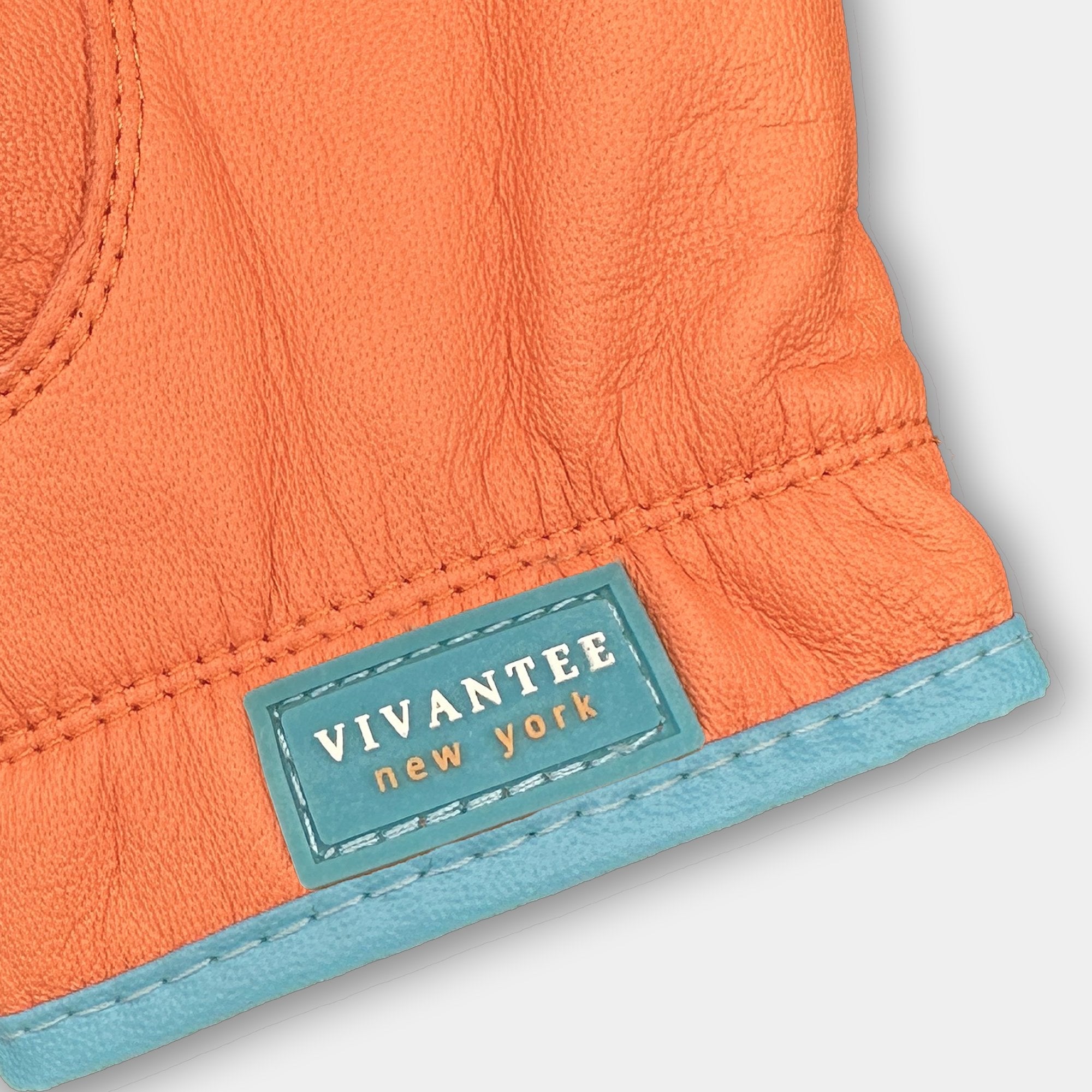 Close-up of orange leather product with 'Vivantee New York' label on a light gray background