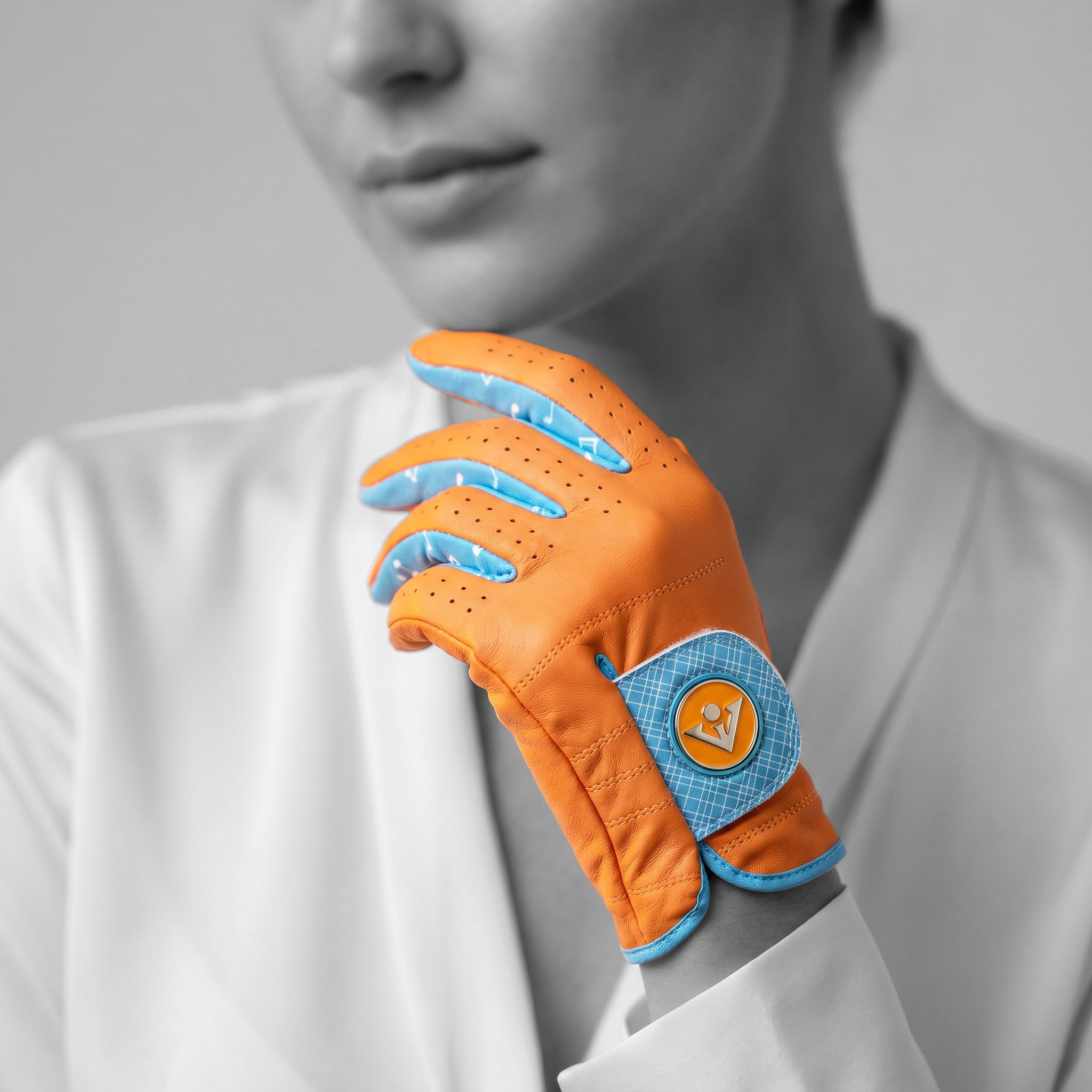 Orange and blue women's golf glove held by a person wearing a white shirt.