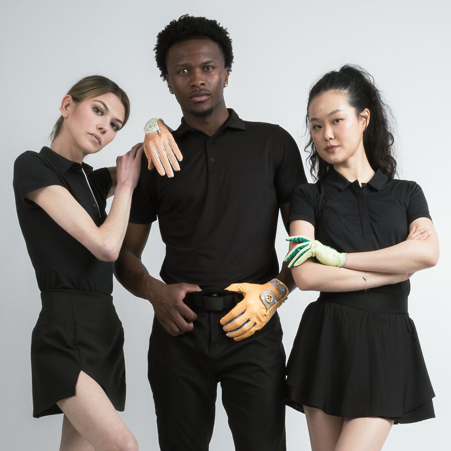 Diverse golfers all wearing black with a white background sporting colorful golf gloves with magnetic ball markers.