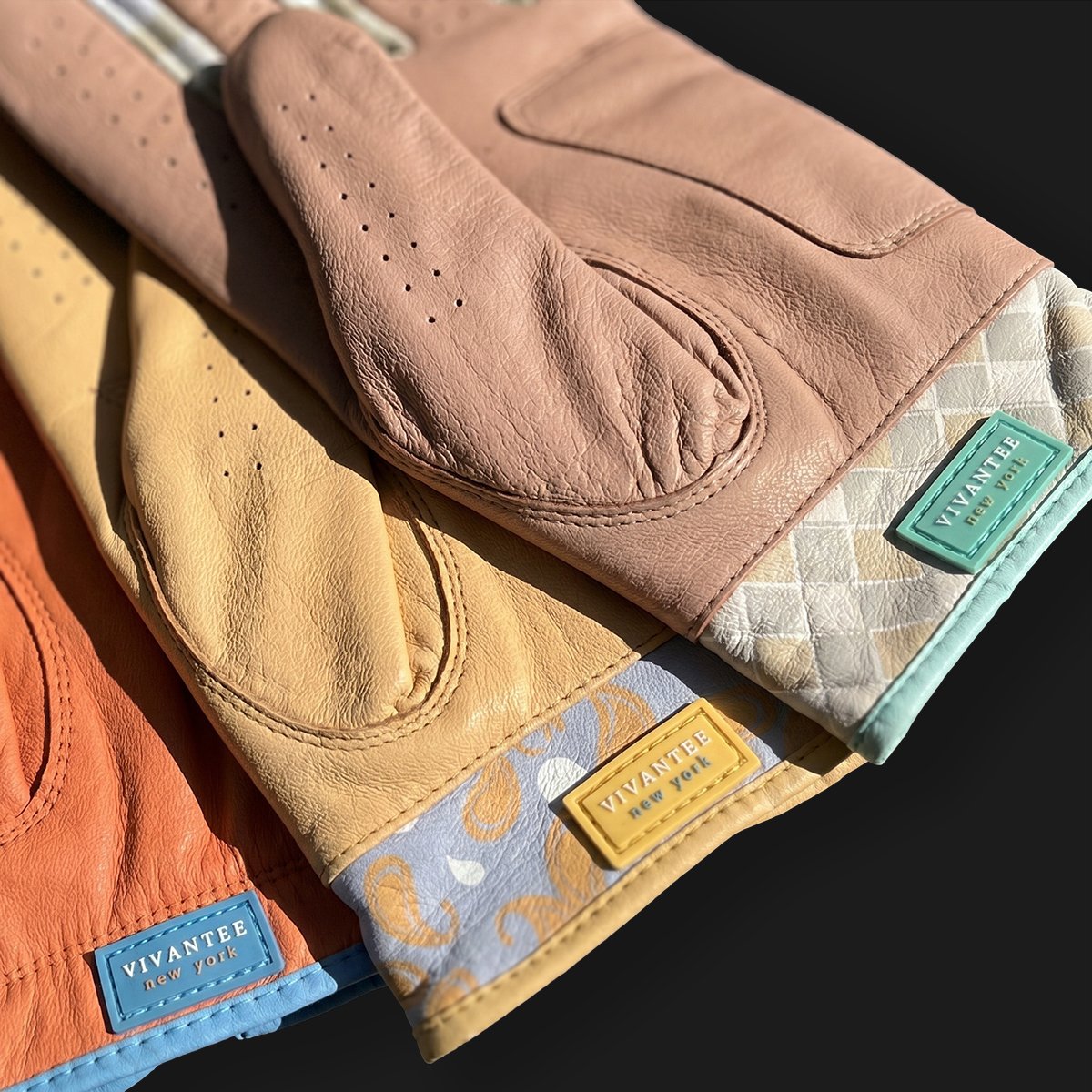 Three leather colored golf gloves with brand labels on a black background.