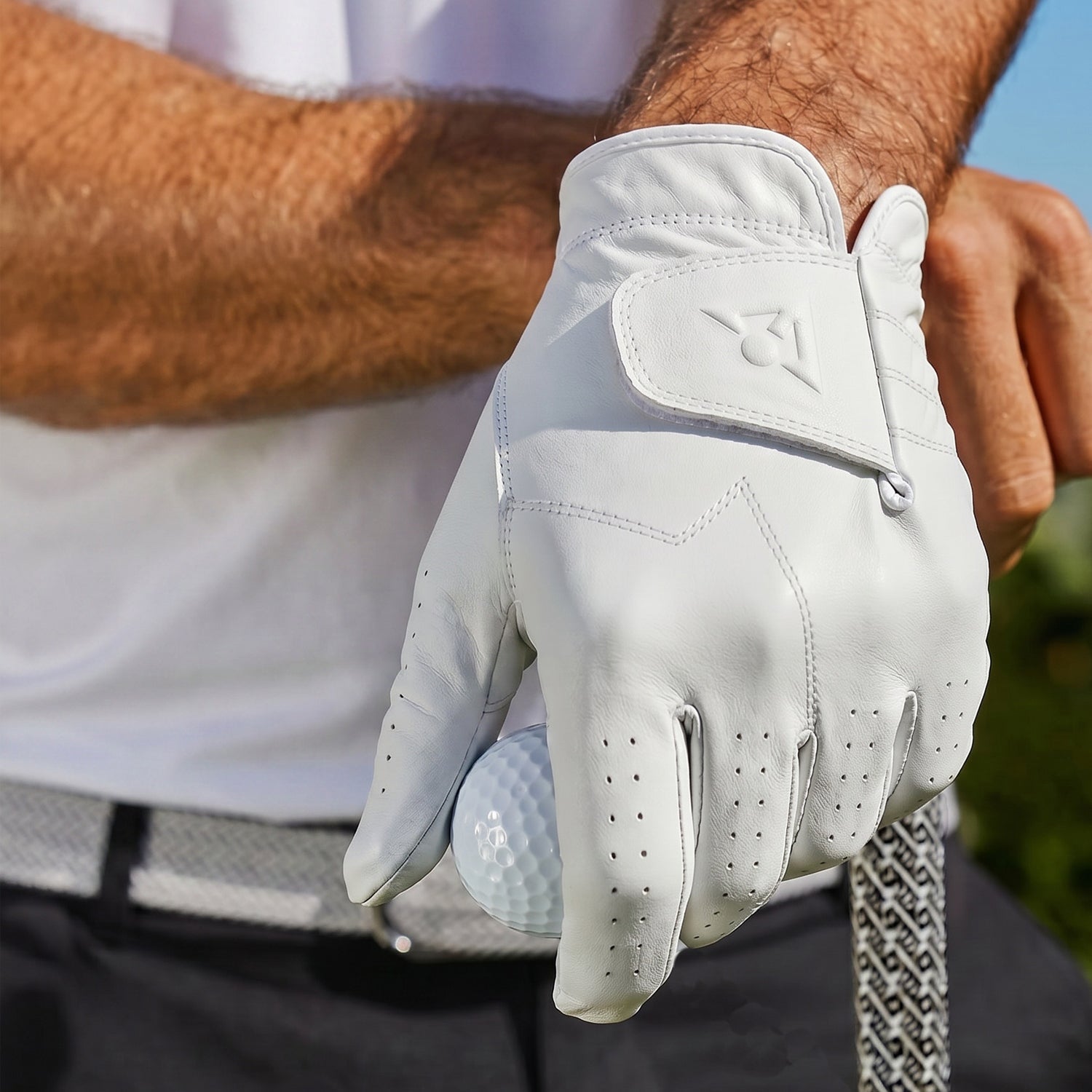 Golf glove holding a golf ball with a blurred background