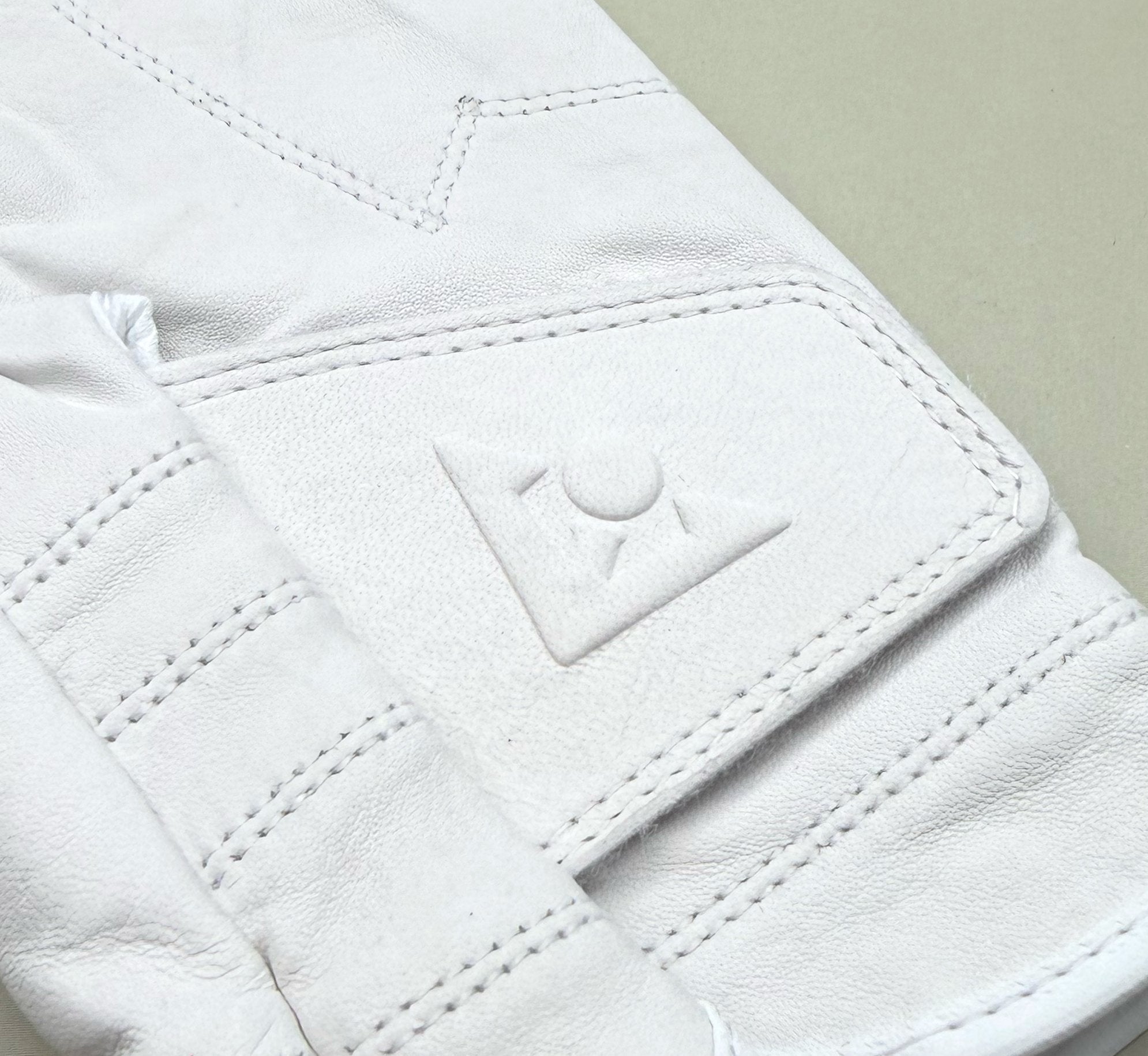 Close-up of a white golf glove with a VivanTee logo on a light gray background