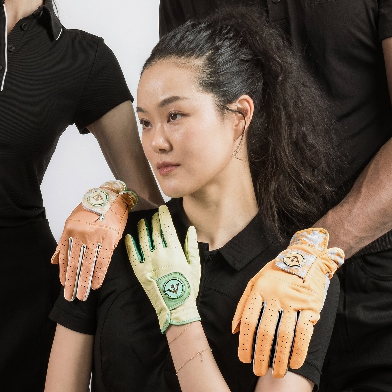 3 models posing and close up on 3 colored golf gloves with ball markers.