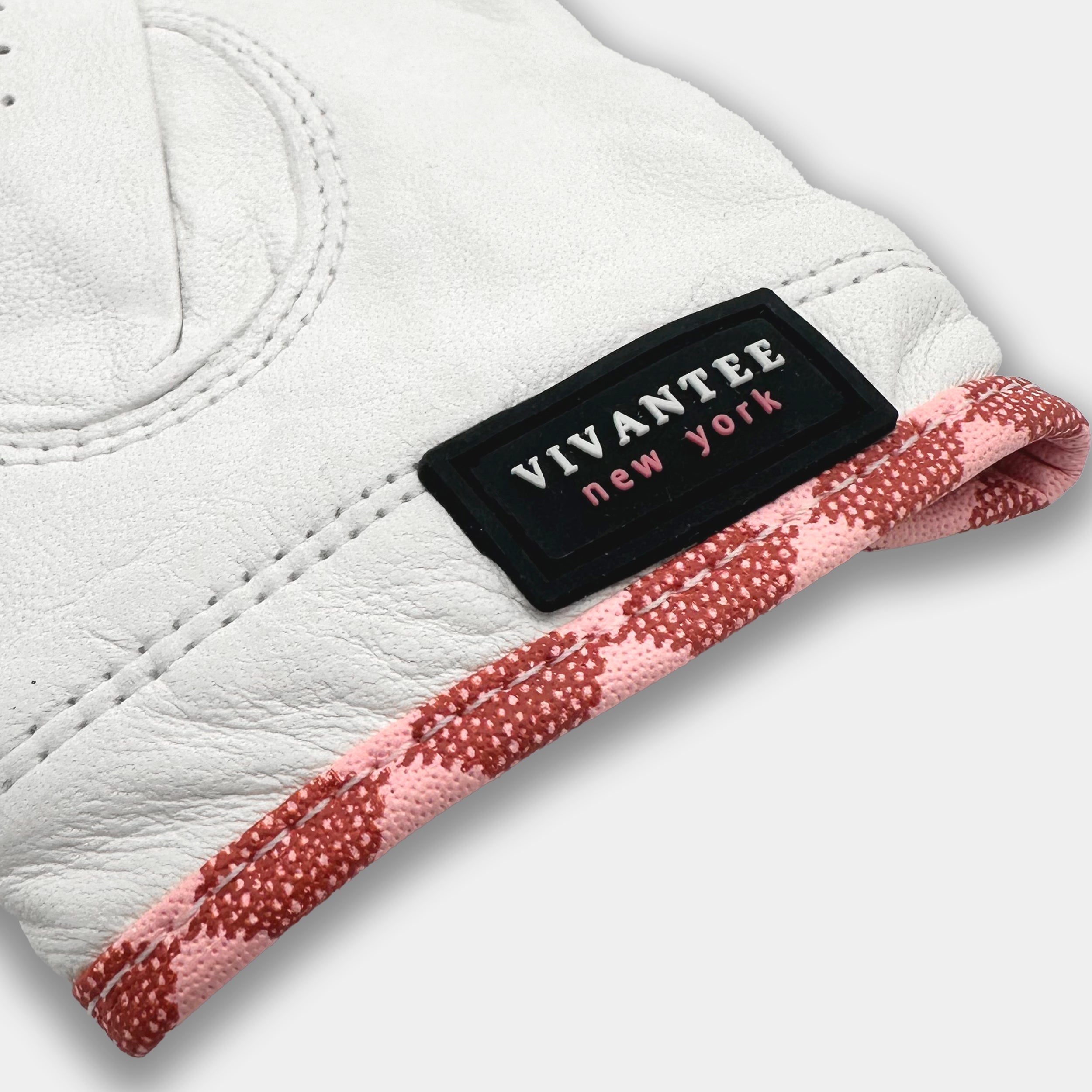 Close-up of a white leather product with a black label reading 'Vivantee New York' on a light gray background.