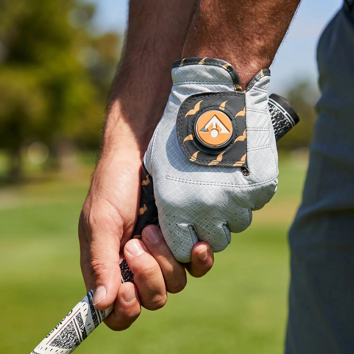 Golf glove with a VivanTee logo on a blurred golf course background