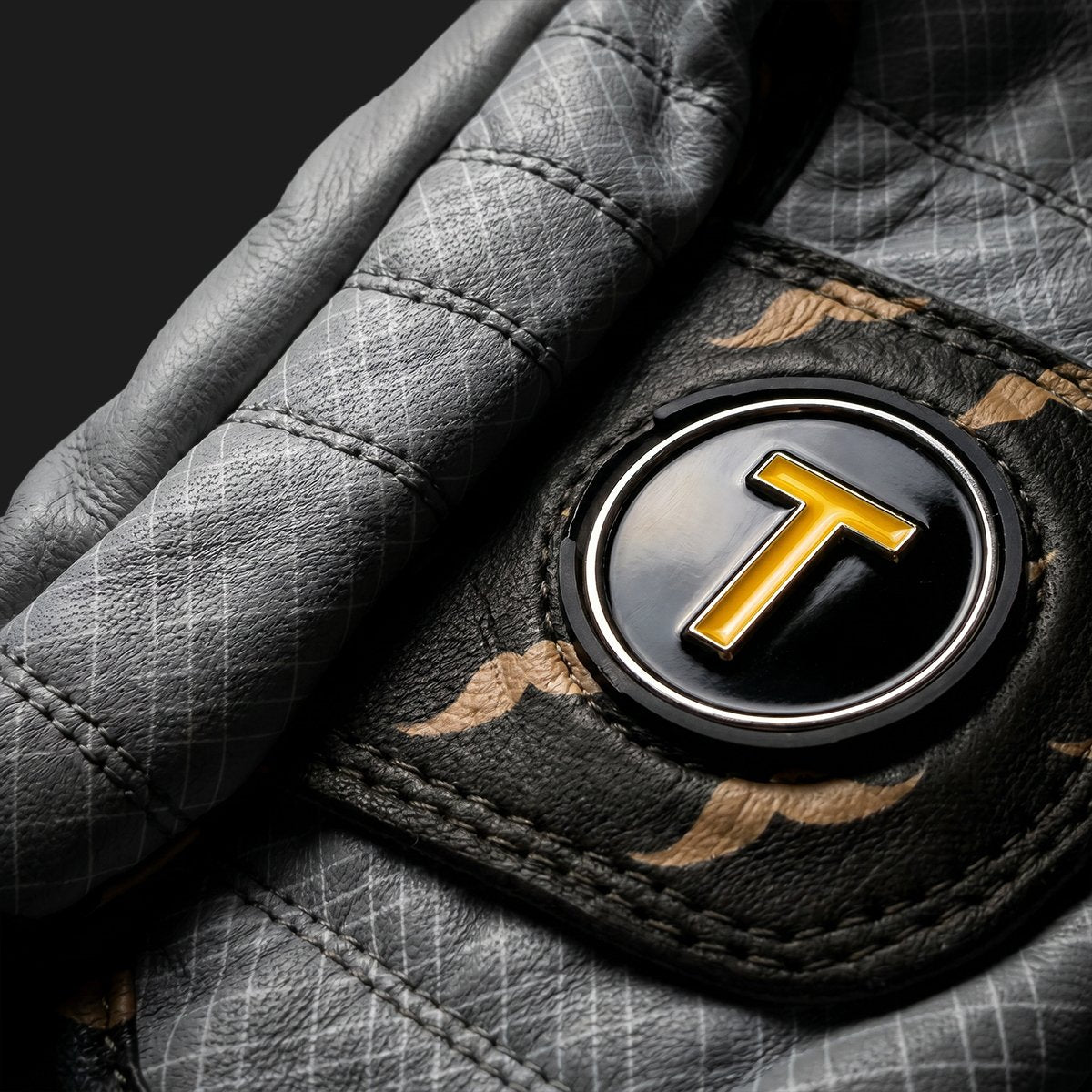 Close up of a gray golf glove with a vinyl record magnetic ball marker on a dark background by VivanTee Golf.