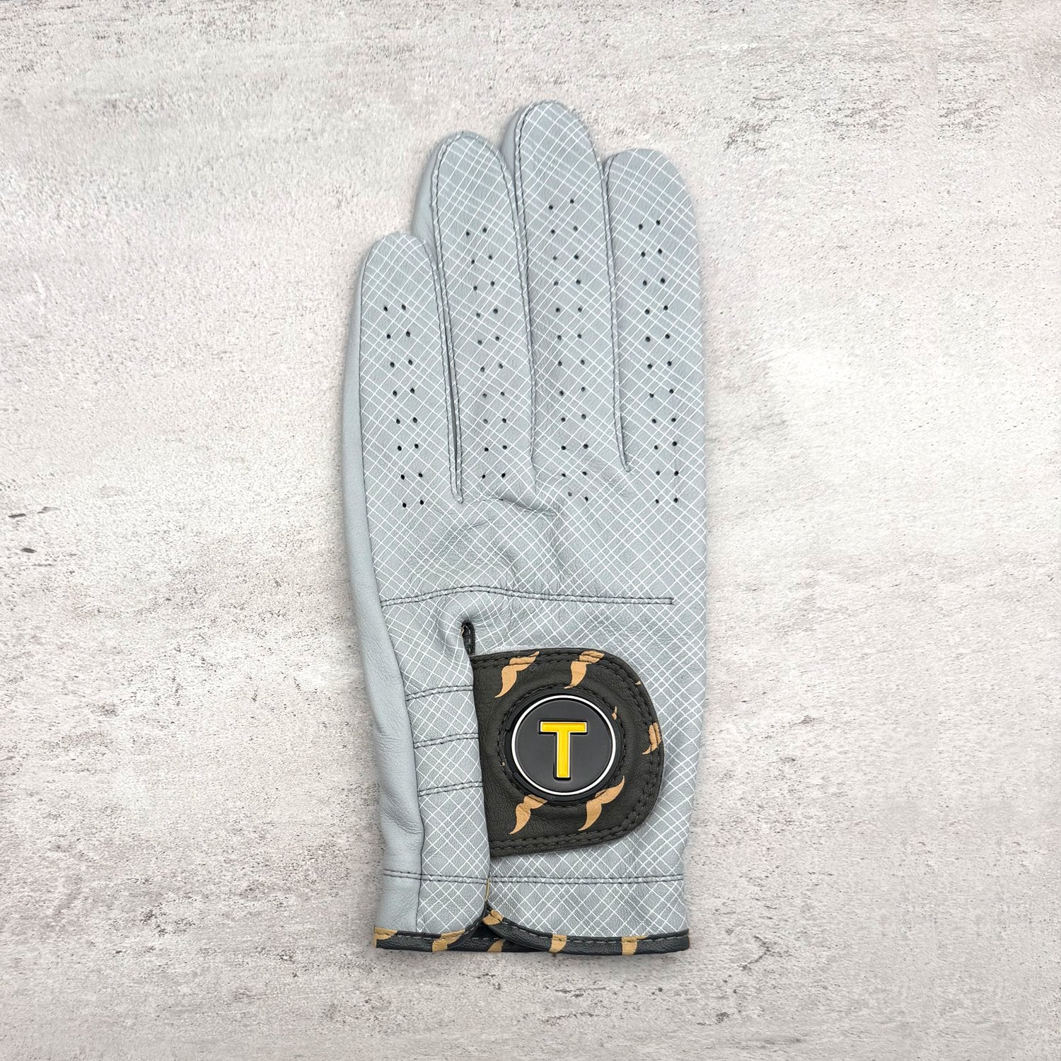 Golf glove with plaid pattern and mustaches in grey and charcoal on granite counter top.