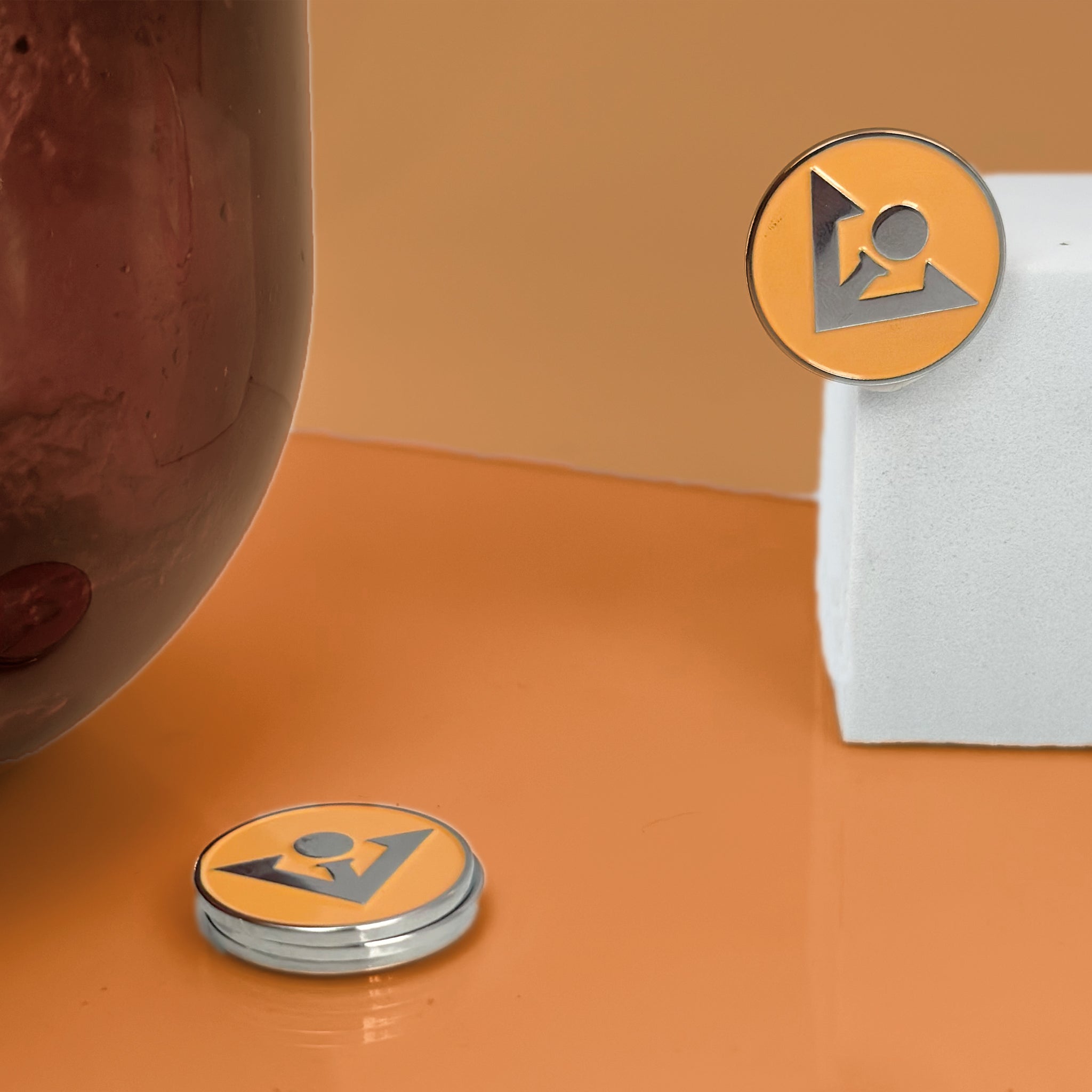 Apricot Crush colored magnetic golf ball marker with orange and brown backdrop. Matching colors with a white square to pop.