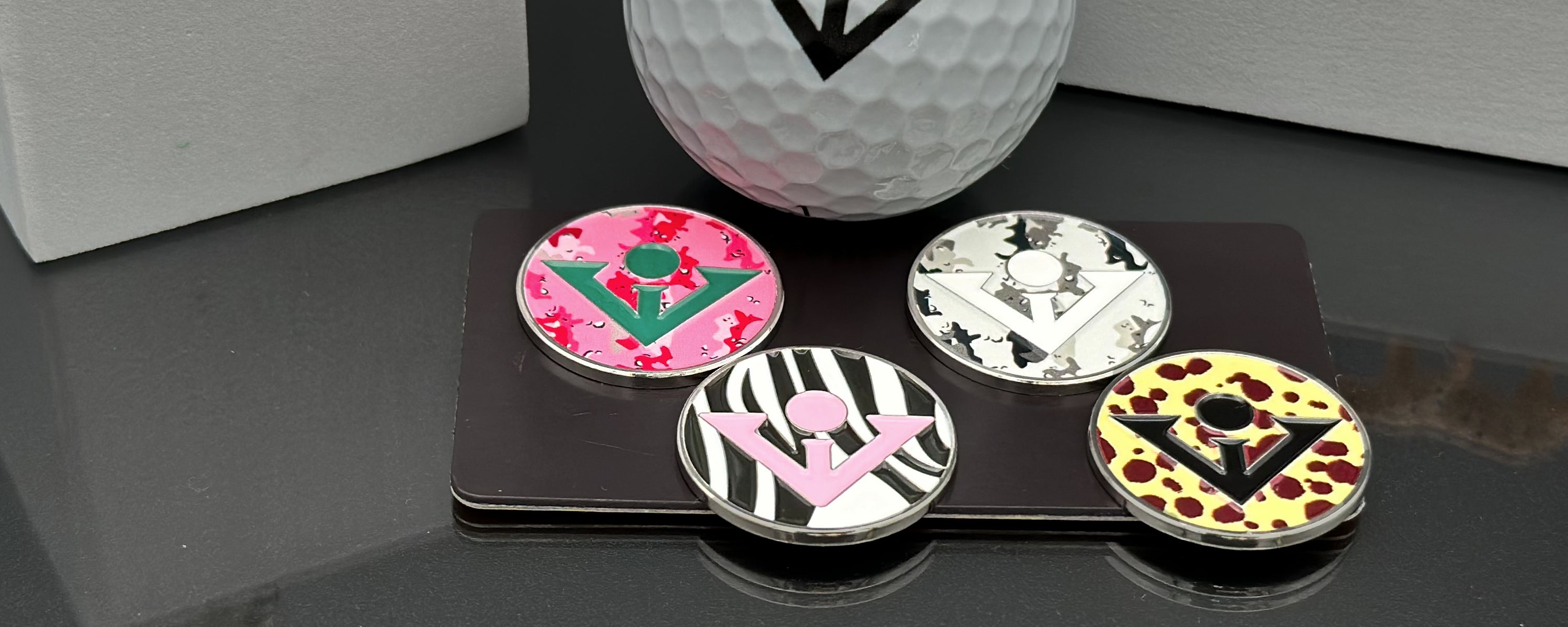Printed magnetic golf ball marker collection lined up with a black and white background, showing the various designs and colors.