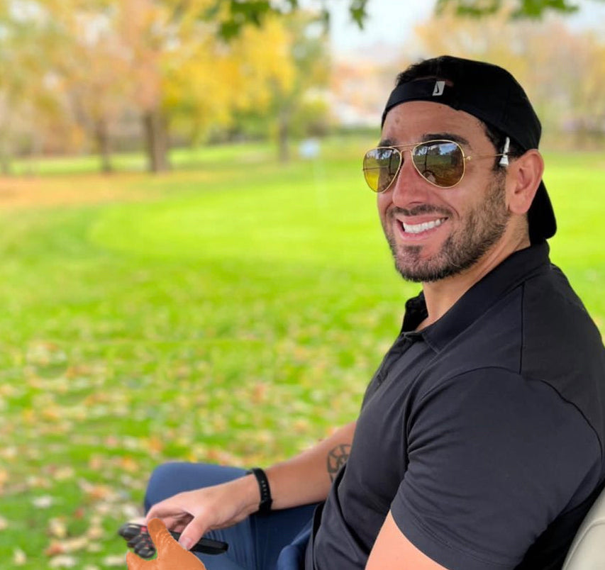 Portrait of VivanTee golf owner in a golf cart with a golf green in background.  