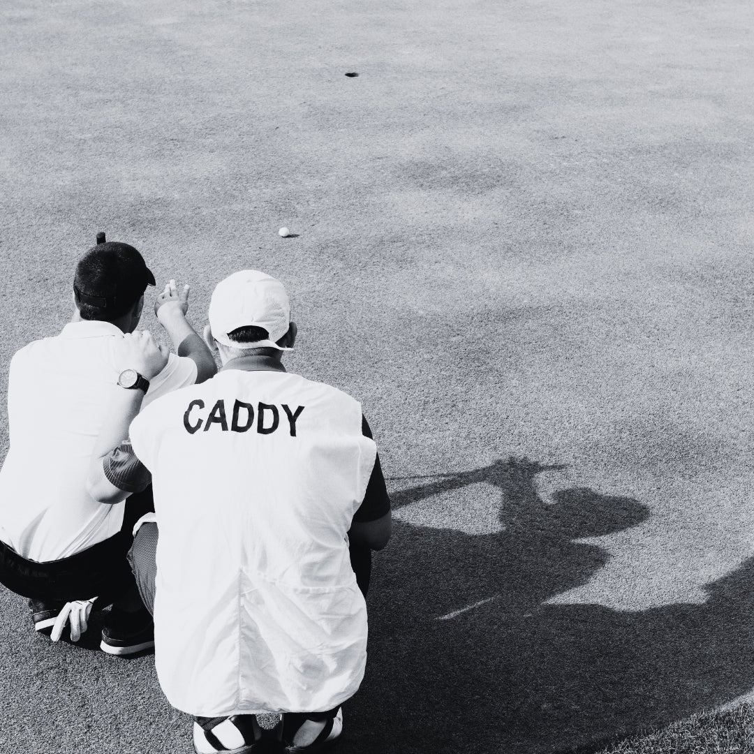 Golfer and his caddie reading a putt in black and white.