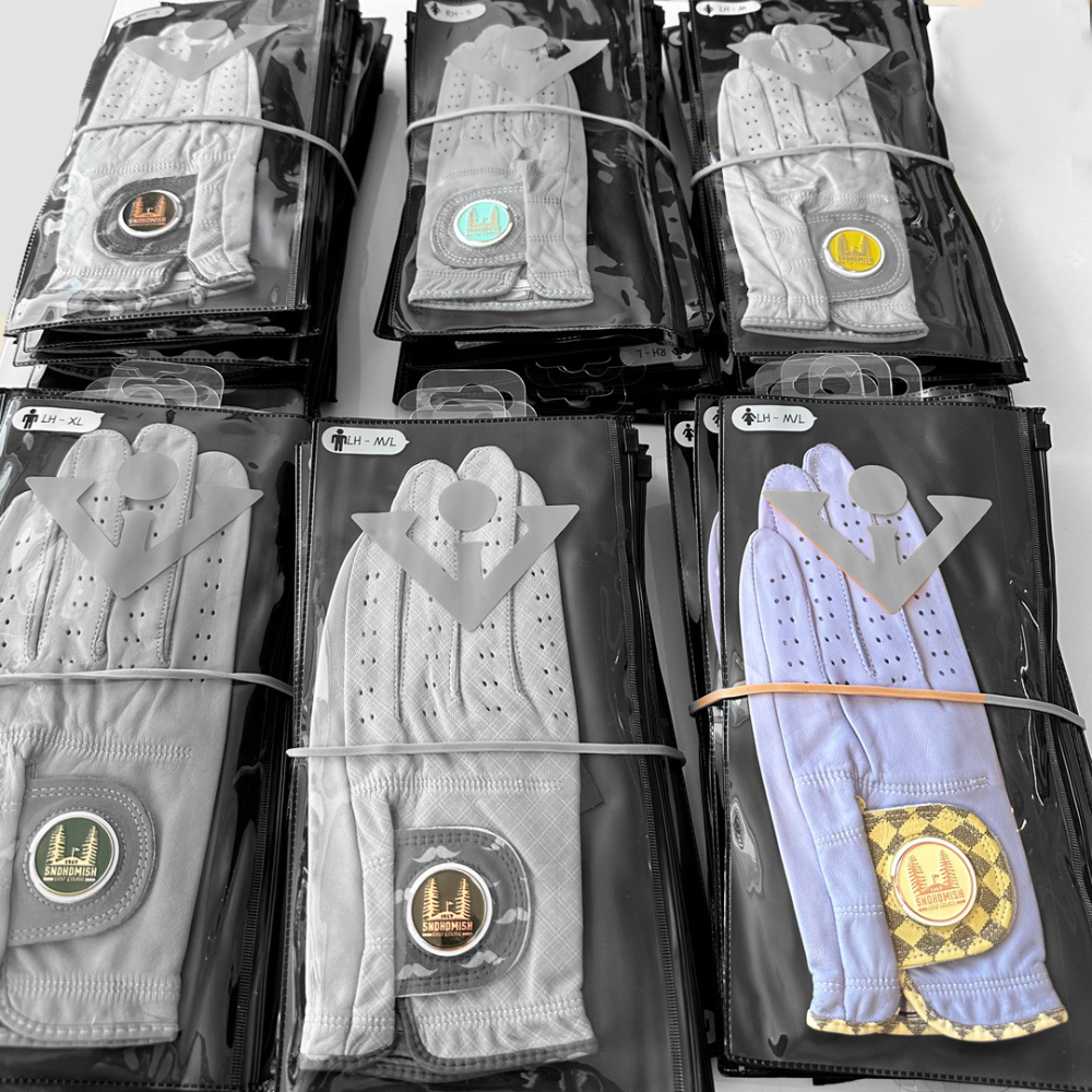 An image of an order of Wholesale golf gloves with a custom golf course logo, featuring one purple glove and the rest in black and white.
