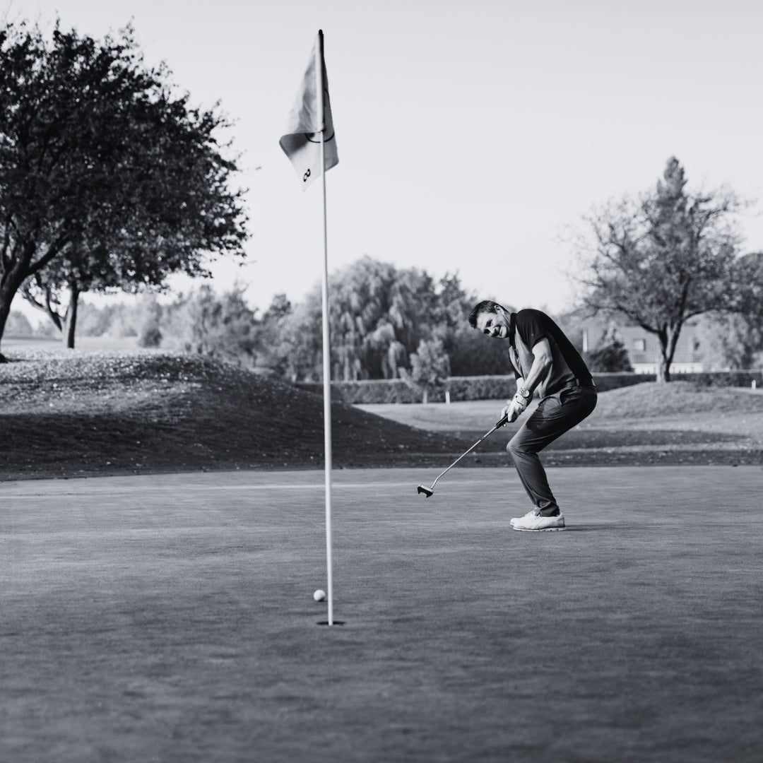 Man missing a putt on a golf green in a monochromatic setting.