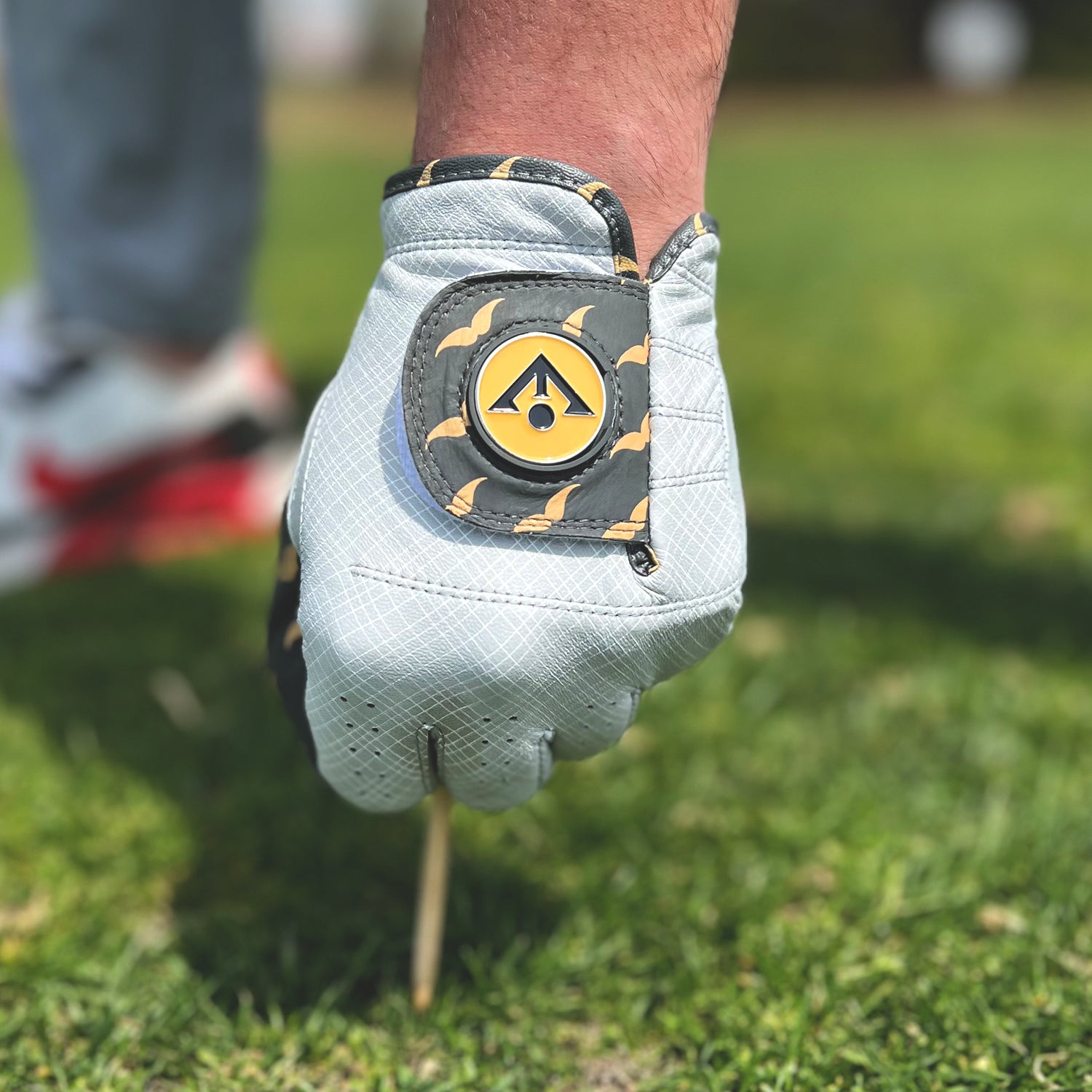 Close up of golf glove with mustache pattern and plaid in charcoal by VivanTee Golf putting a tee in the ground.