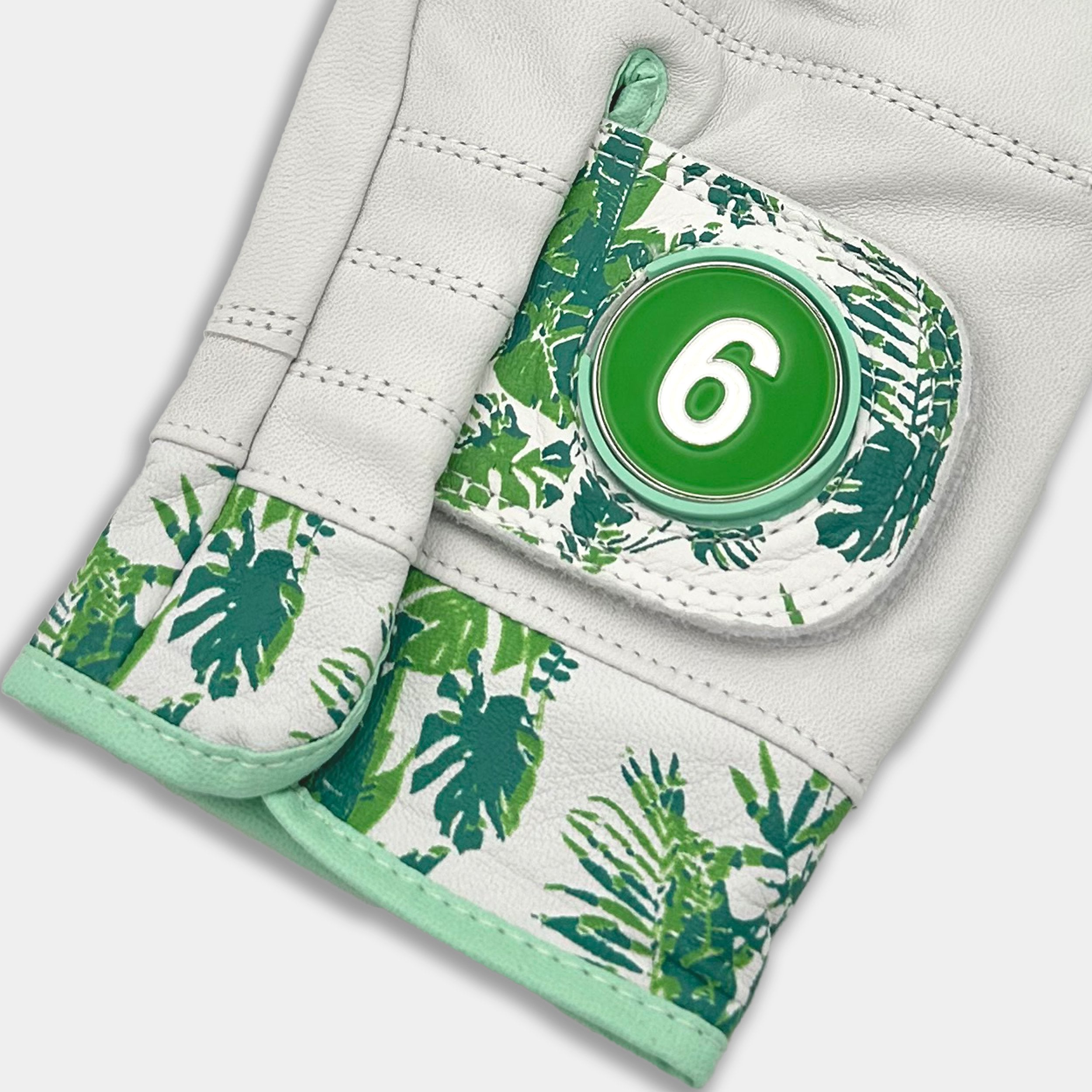 Glove with green leaf pattern and a button on a white background.