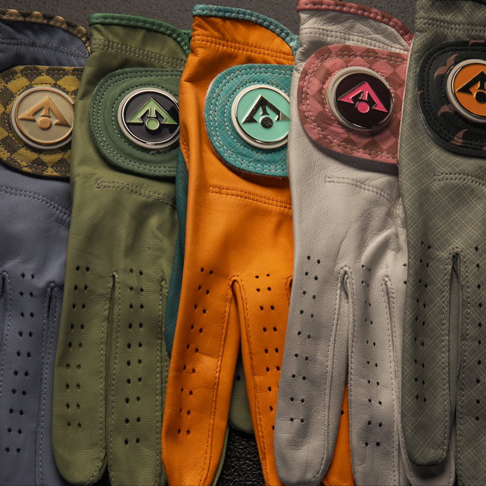 All magnetic golf gloves with ball markers laid out in multiple designs and colors, with orange one the brightest.