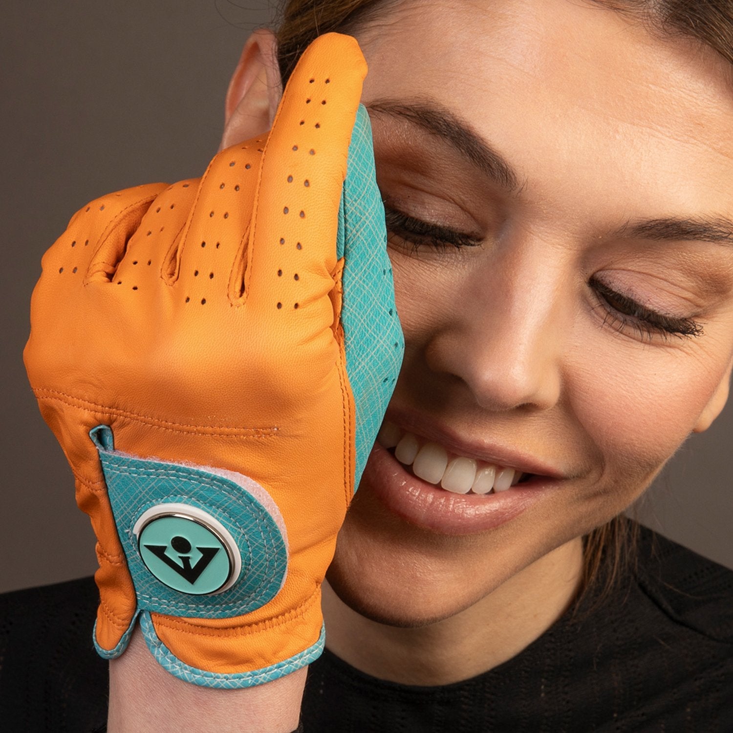 Model smiling with an orange woman's golf glove close up in front of her face.