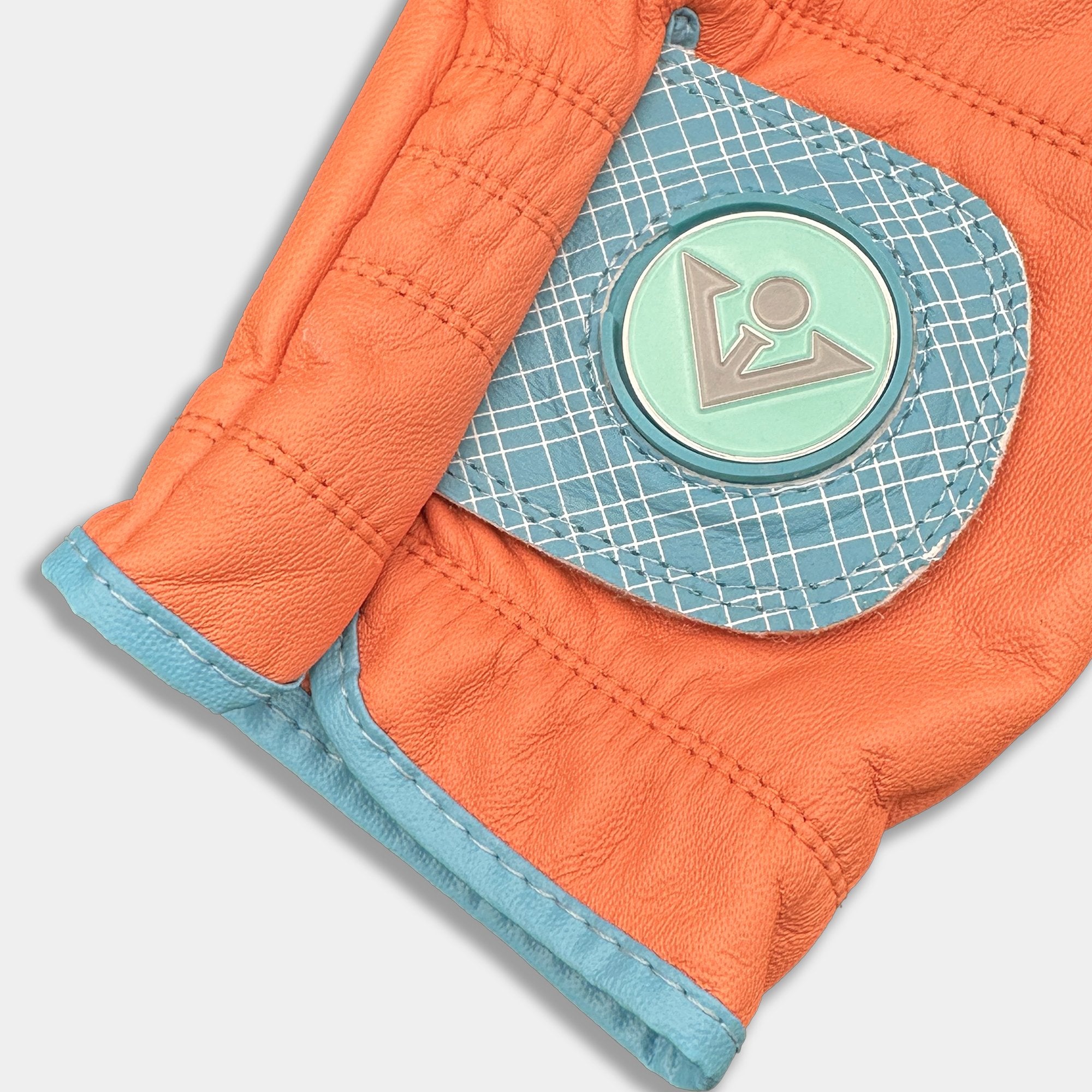Close up of VivanTee orange golf glove with magnetic ball marker in blue on a white background.