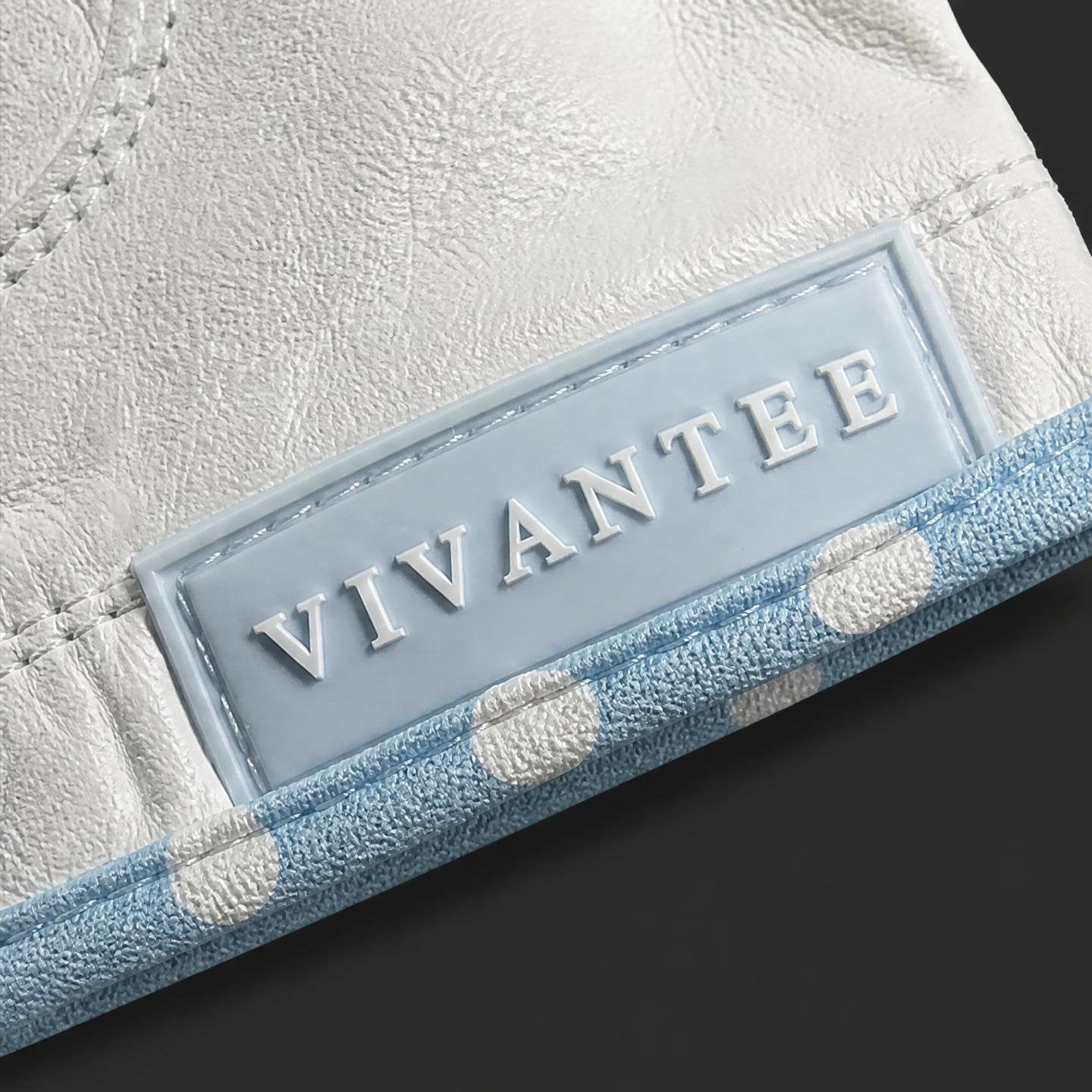 Close-up of a light blue pull tab with brand name VIVANTEE on a textured off-white leather surface.