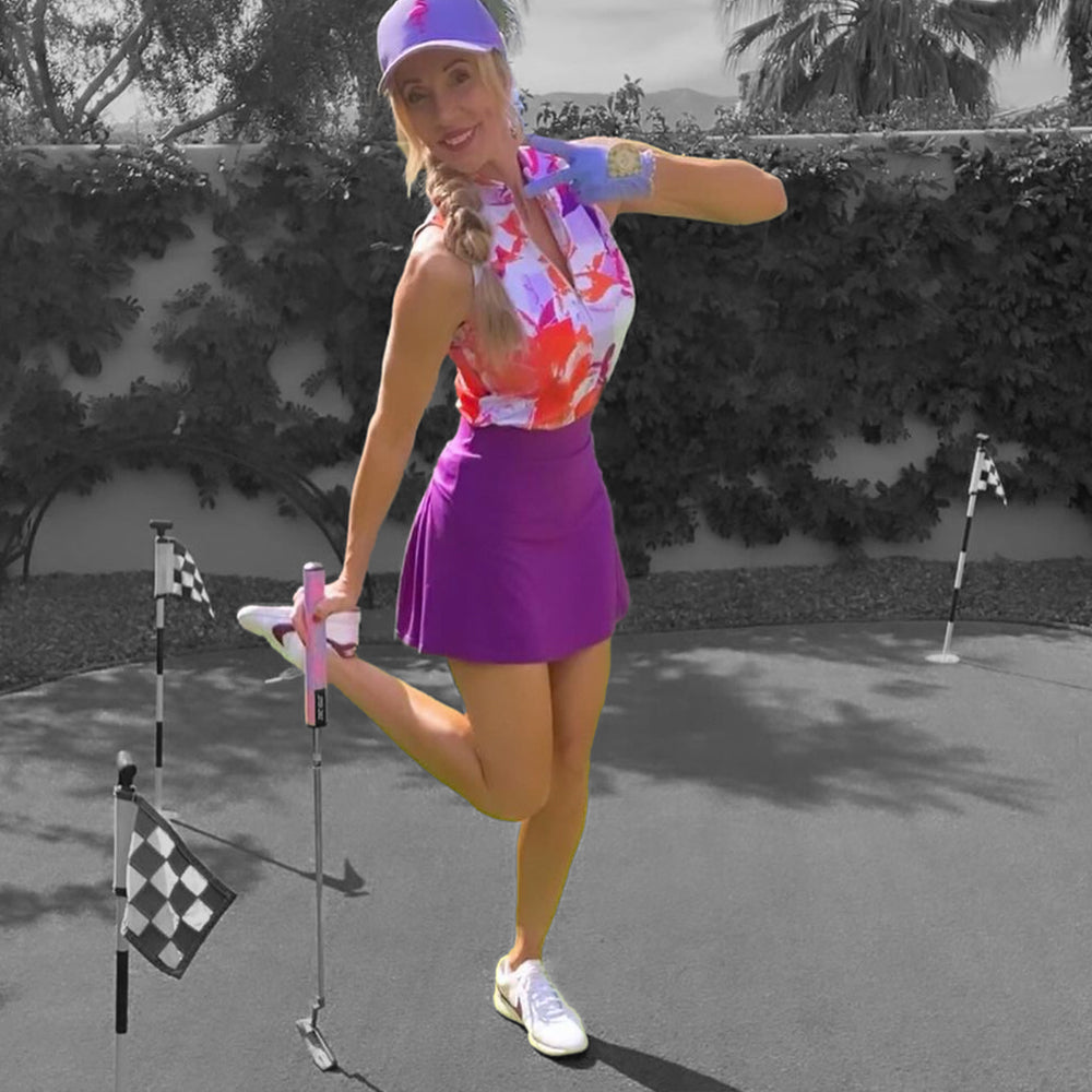Woman in various color prints of pink and purple holding up a piece sign with her VivanTee golf glove with ball marker.