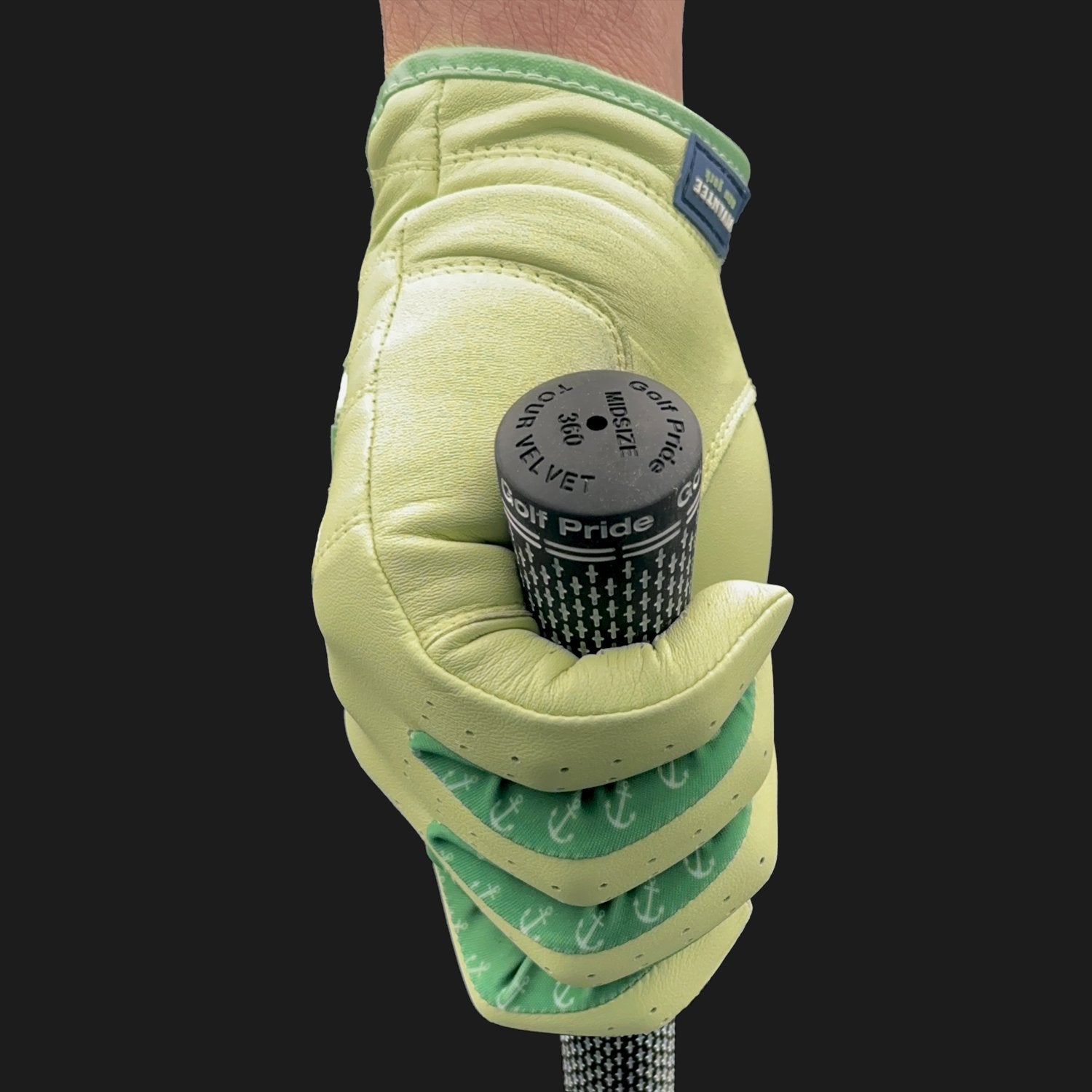Hand wearing a green golf glove with lycra holding a golf club head cover against a black background.