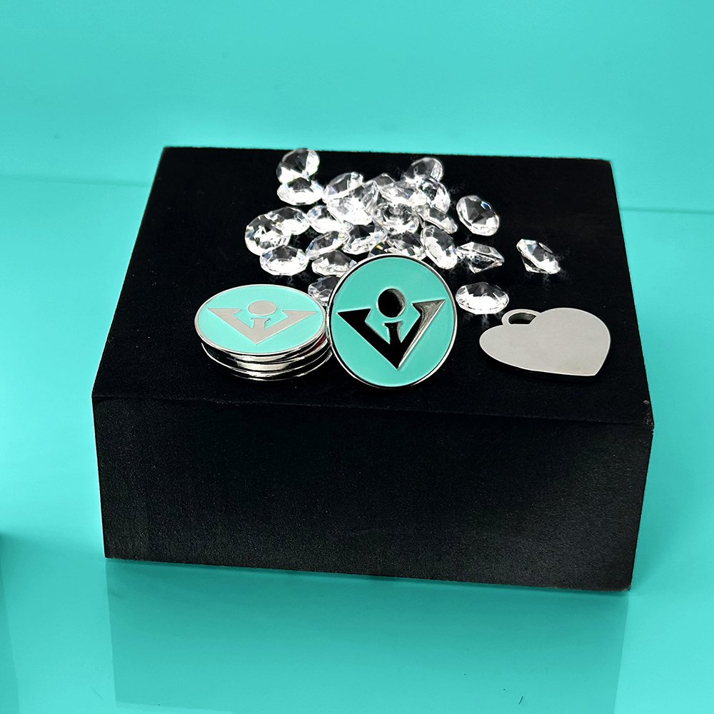 Elegant presentation of metallic golf ball markers with a sleek design, set on a black display box against a Tiffany blue background, accentuated with scattered crystal decorations the perfect partner for our magnetic golf gloves.