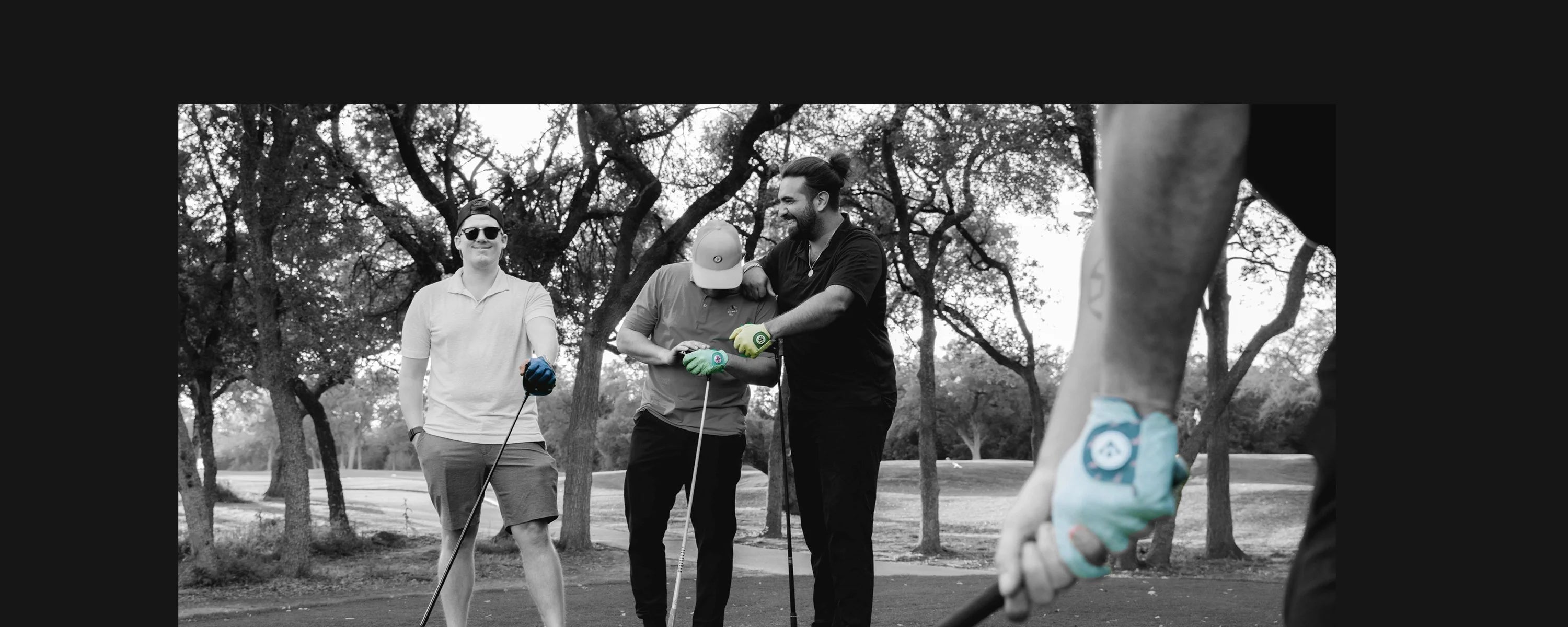 Men golfing on the tee box waiting with someone lines up in monochromatic showing unique golf gloves with magnetic ball markers in various colors.