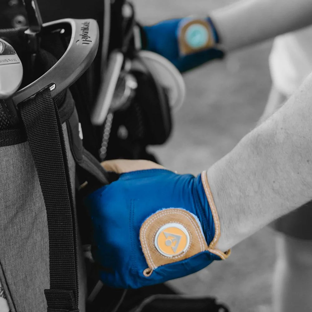 Two midnight blue golf gloves with orange ball markers grabbing a golf bag in monochromatic back drop.