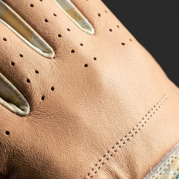 Close-up of a brown leather golf glove with a brand logo on a dark background