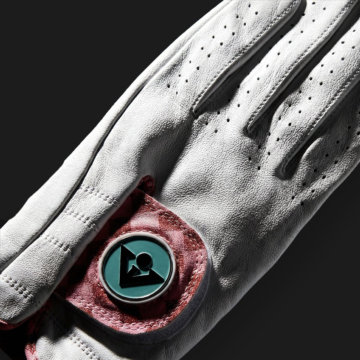 Close-up of a white leather golf glove with a brand logo on a black background