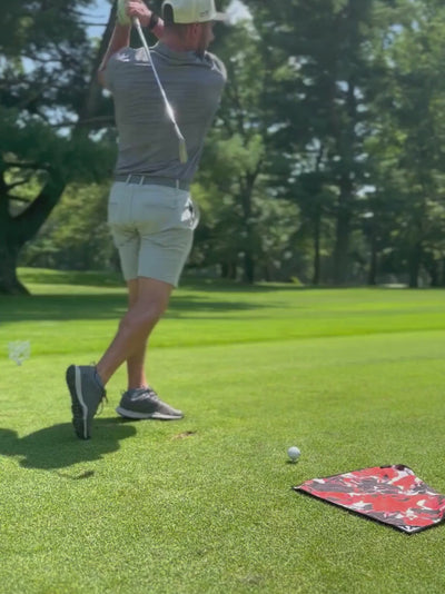 Golfer taking practice swings and then using his club to pick up his magnetic golf towel showing the convenience and vibrant colors.