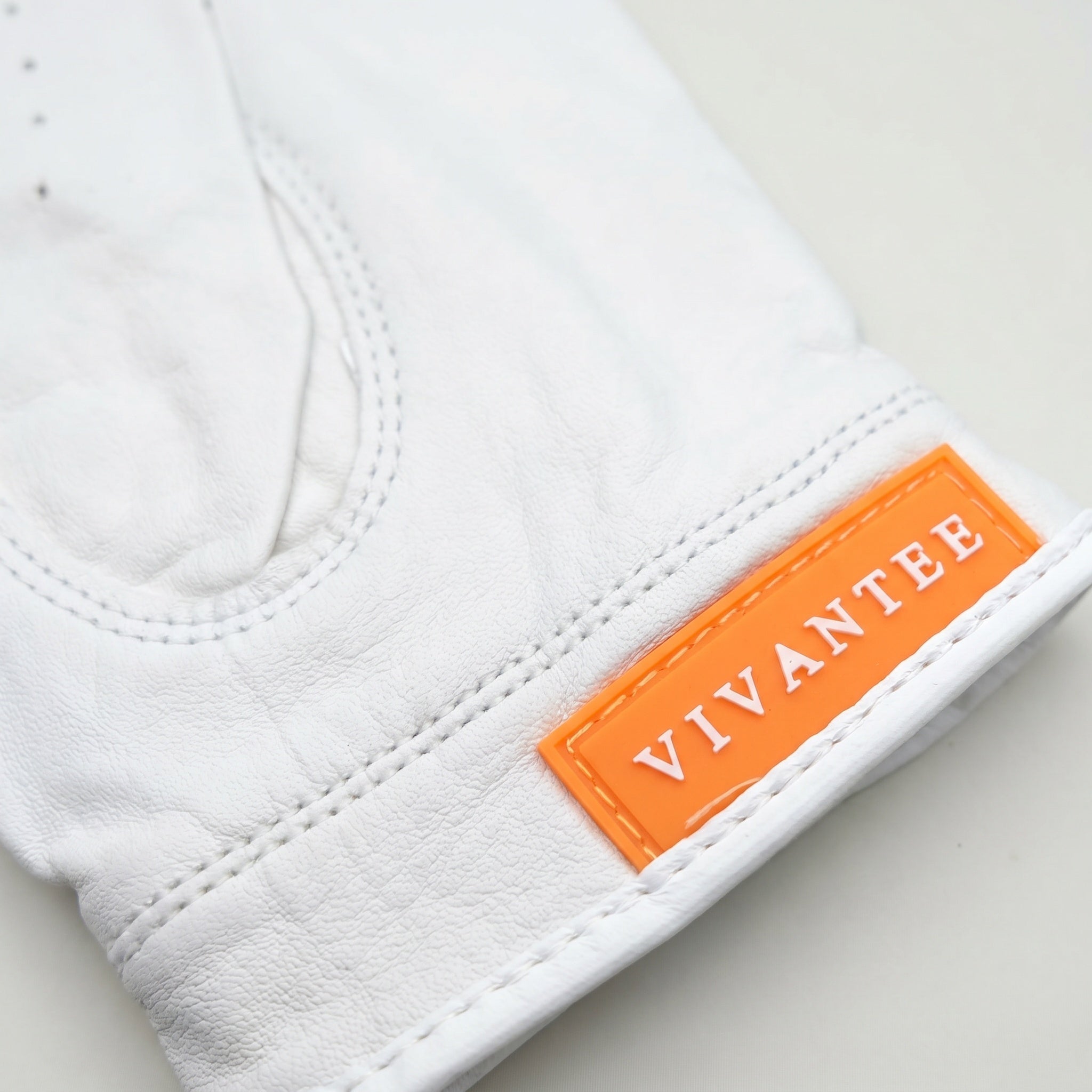 White golf glove with an orange 'Vivantee' label on a light gray background