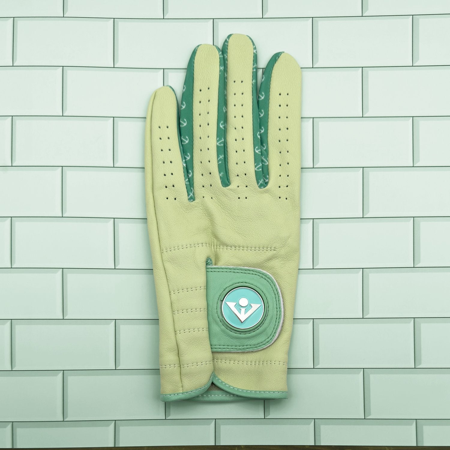 Seaport green golf glove laid out on green tile with magnetic ball marker.