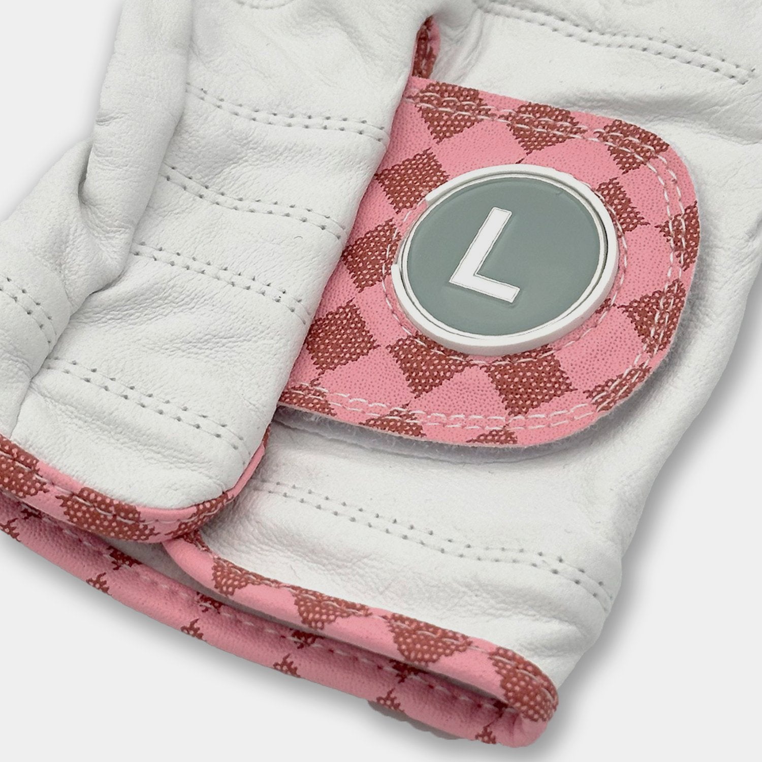 White golf glove with pink and brown patterned palm and wristband, featuring a letter 'L' emblem.