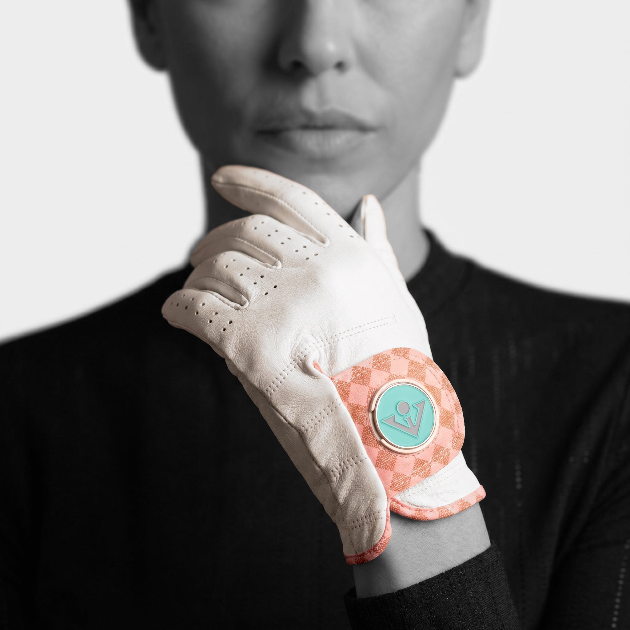 Woman wearing a white golf glove with a pink and green design on a black background