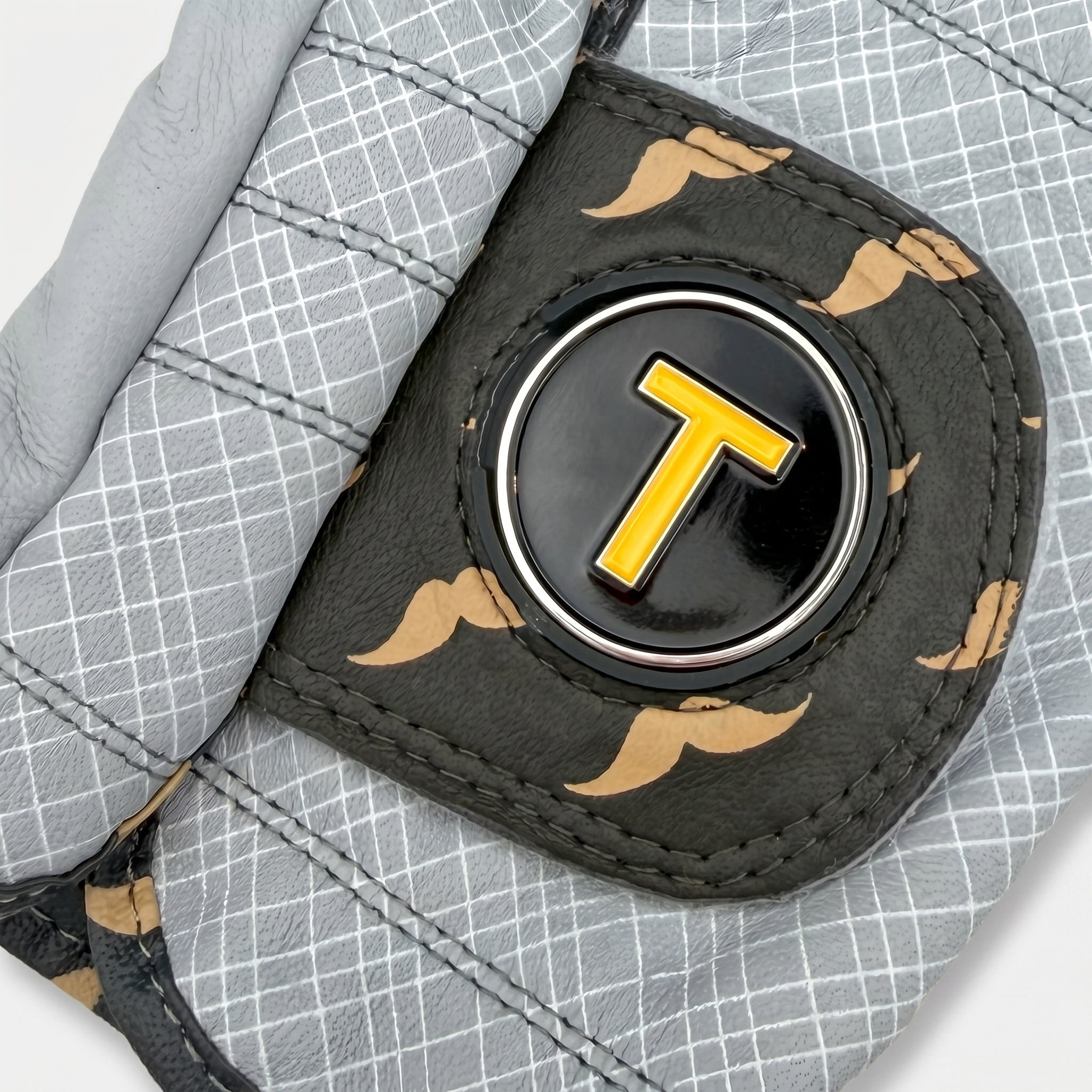 Close up of golf glove pull tag with orange magnetic ball marker with a stylish mustache pattern.
